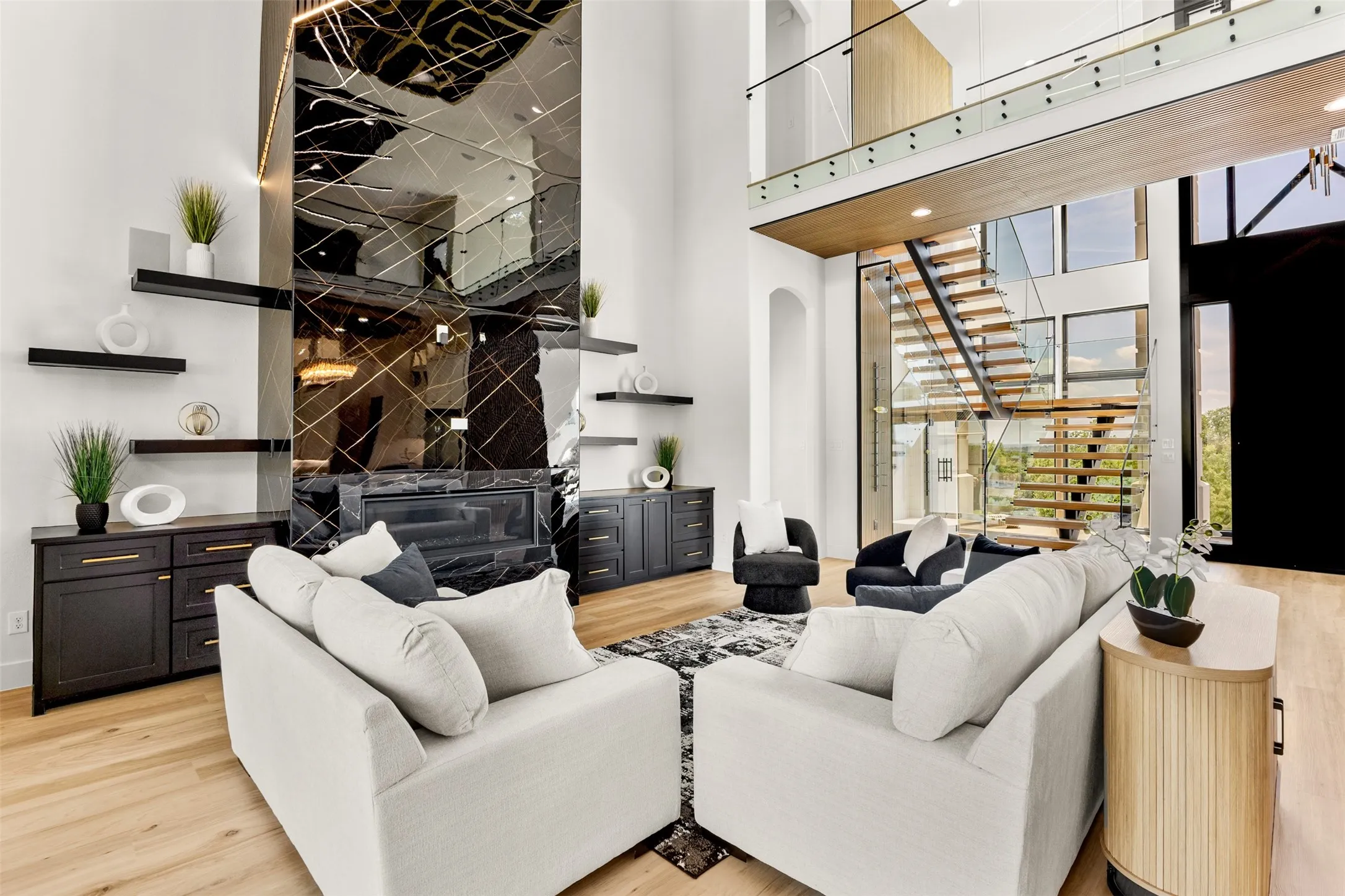 Soaring two-story living space featuring a mirrored accent wall with an integrated fireplace