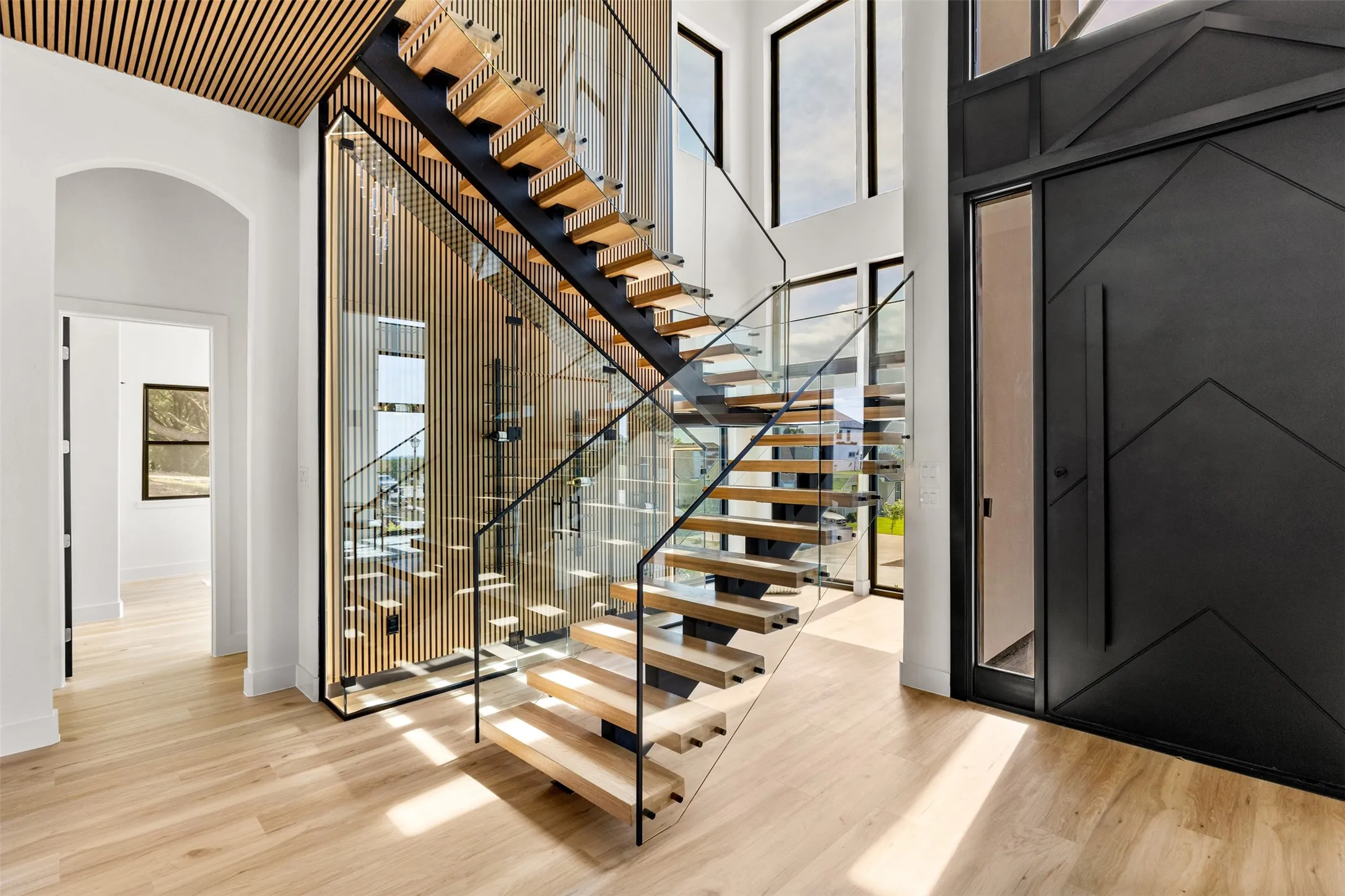 Foyer featuring a floating staircase with wood-finish treads and glass railings