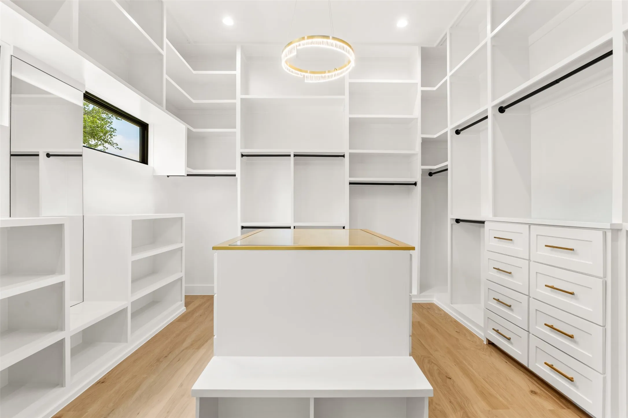 Custom closet system featuring extensive shelving, hanging rods, and built-in drawers with gold-tone hardware