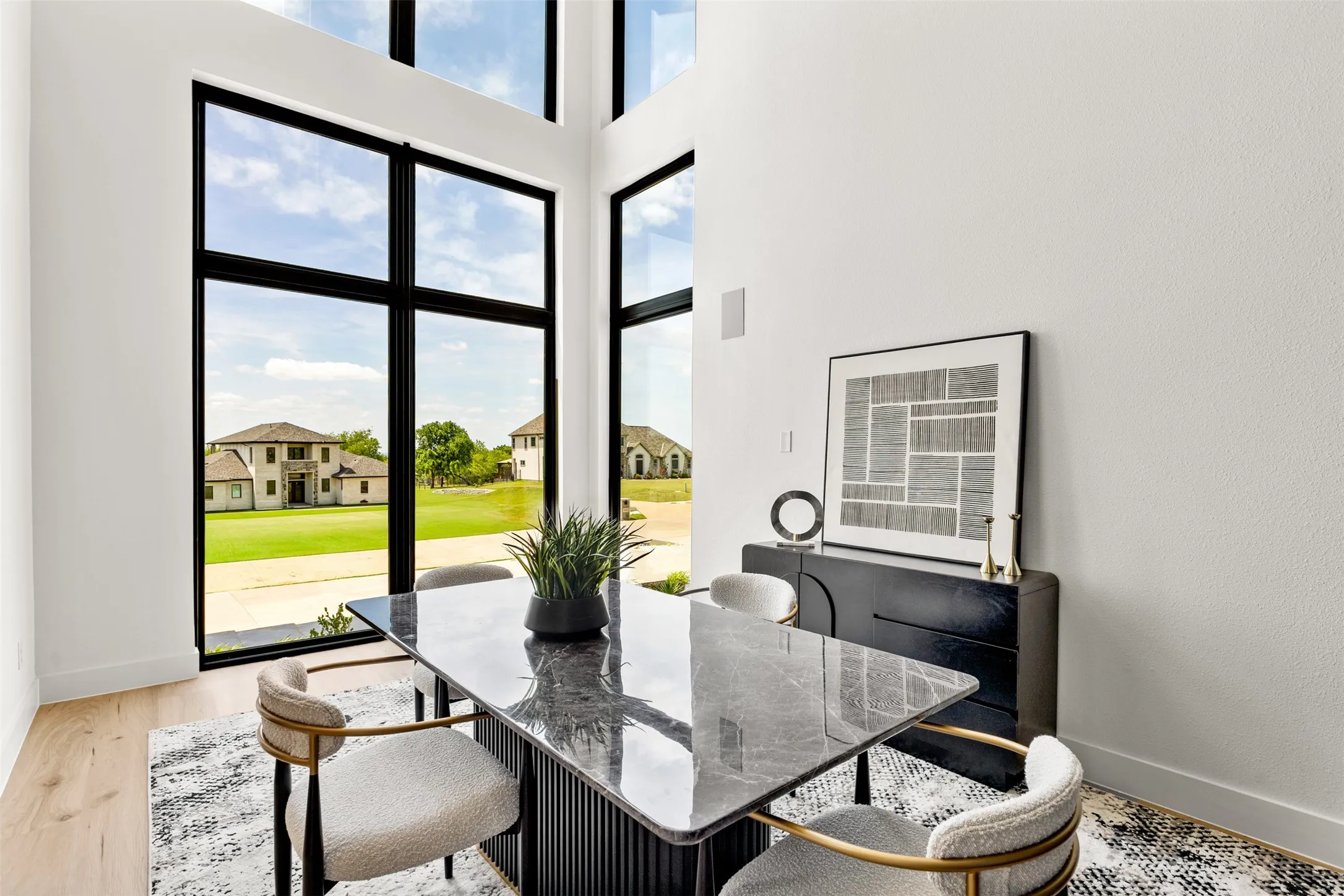 Two-story window wall with black trim, light wood-finish flooring, white walls, and a built-in wall speaker