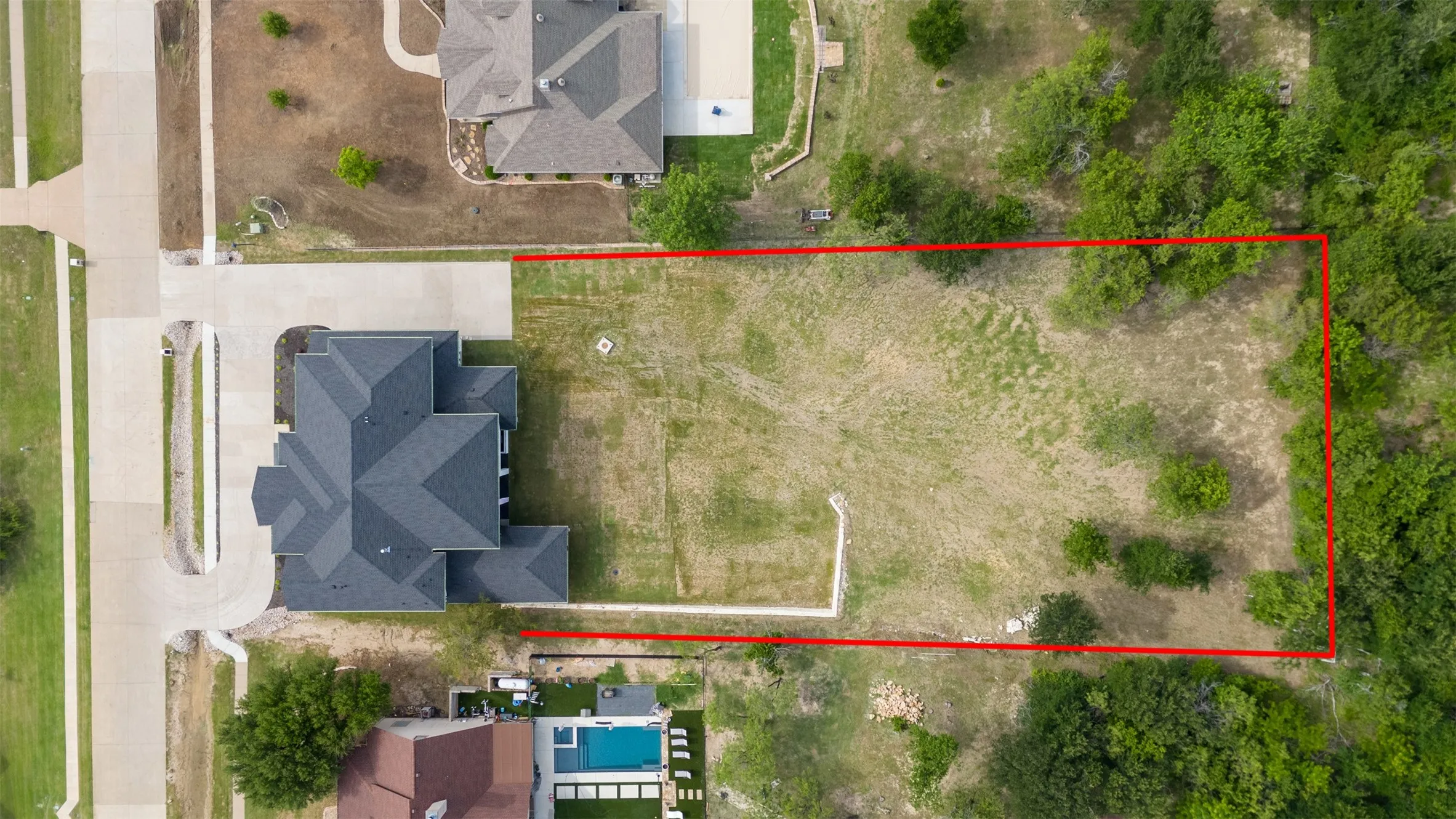 Expansive lot featuring a cleared building site, mature perimeter trees, and direct street access