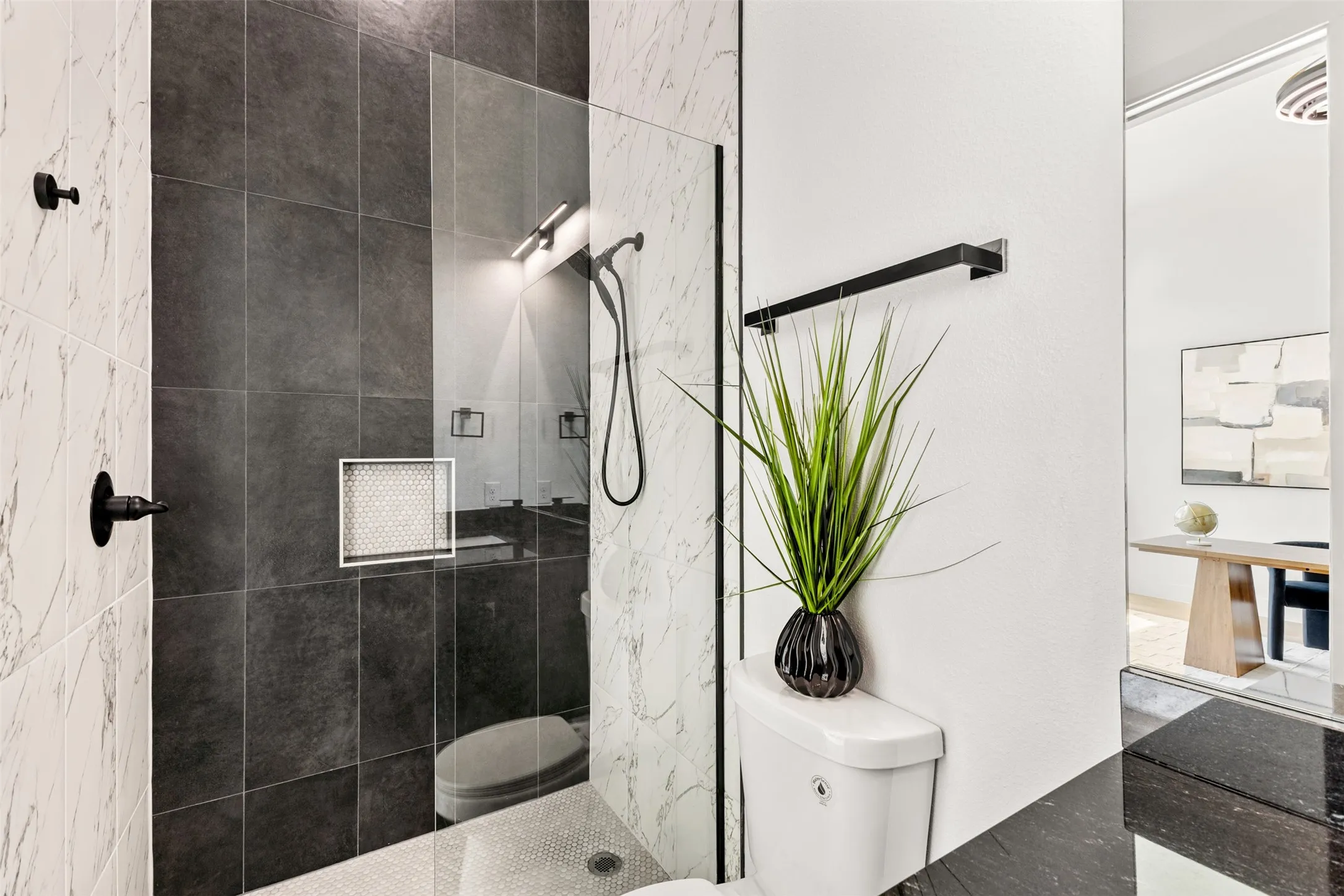 Contemporary shower enclosure featuring a clear glass panel, dark large-format wall tiles, white marble-look wall tiles, a built-in shower niche, and a contrasting hex tile shower floor