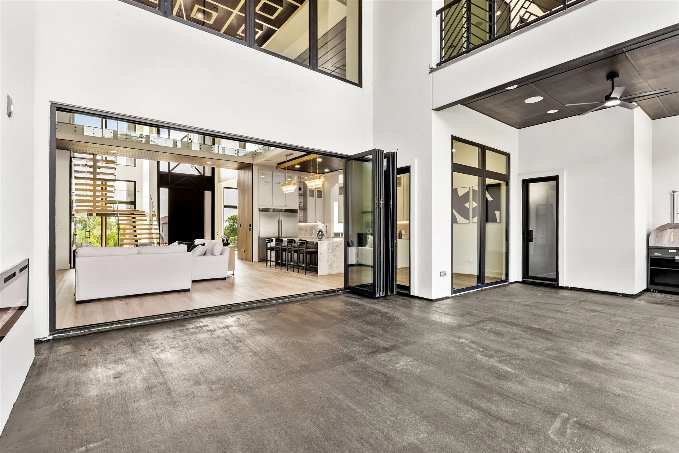 Expansive living area featuring bi-fold glass doors, high ceilings, and polished concrete flooring