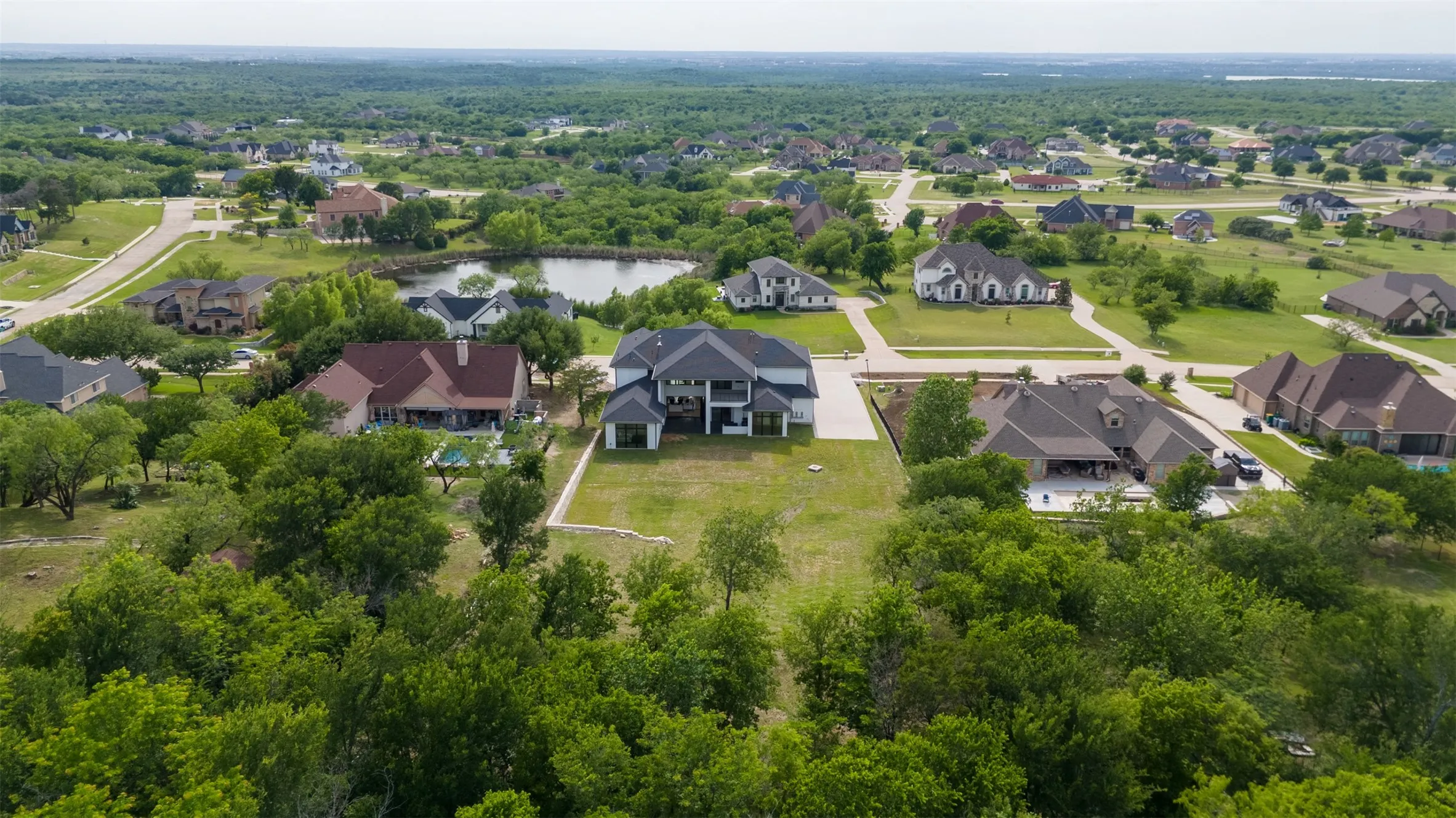 Expansive aerial perspective showcasing a neighborhood with custom homes amidst lush green landscapes and mature trees