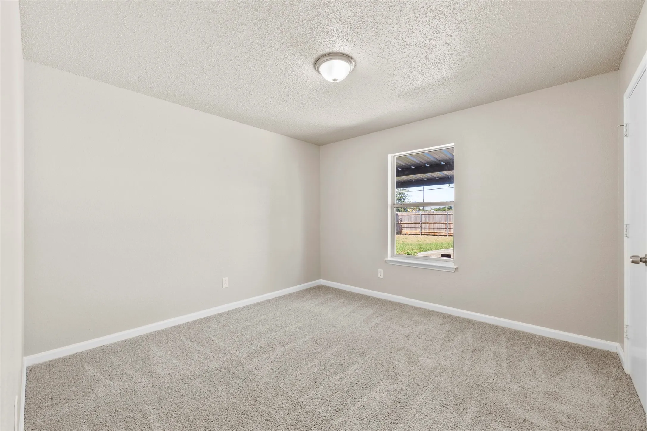 Spacious room featuring neutral carpeting, light-colored walls, and a single window