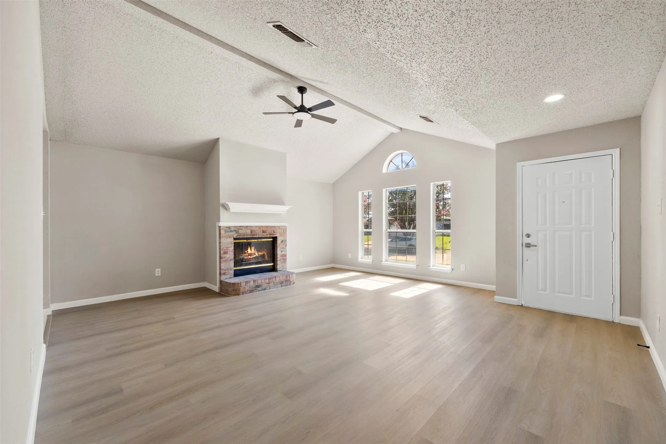 Spacious living area featuring a vaulted ceiling and wood-finish flooring