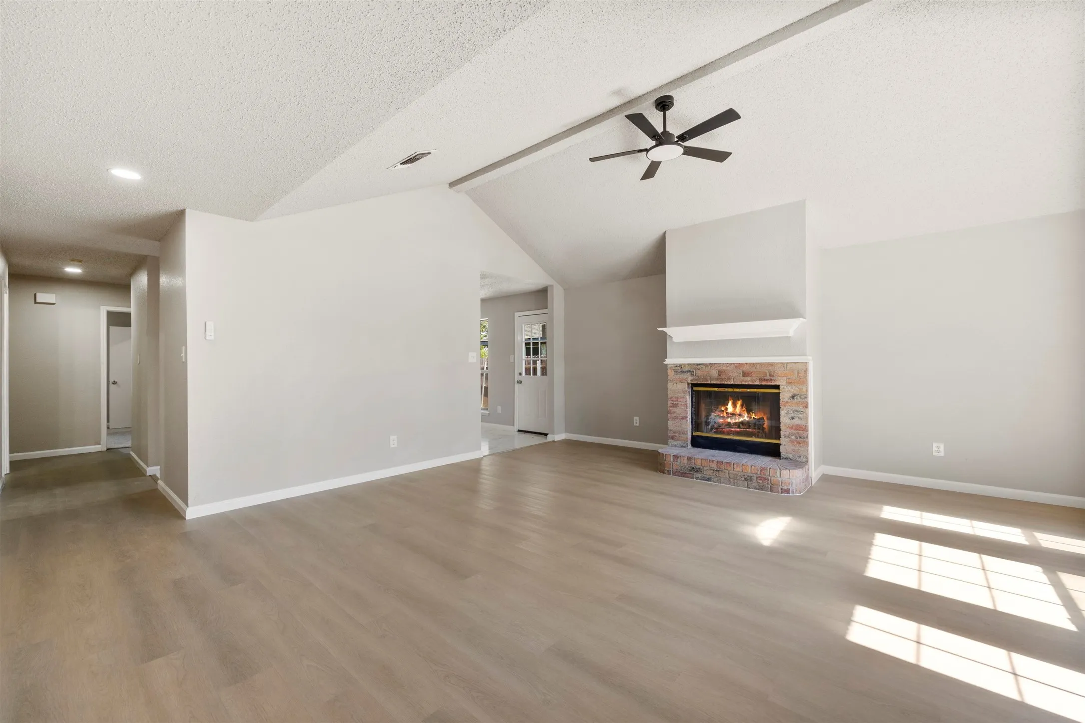 Spacious living area featuring a vaulted ceiling and wood-finish flooring