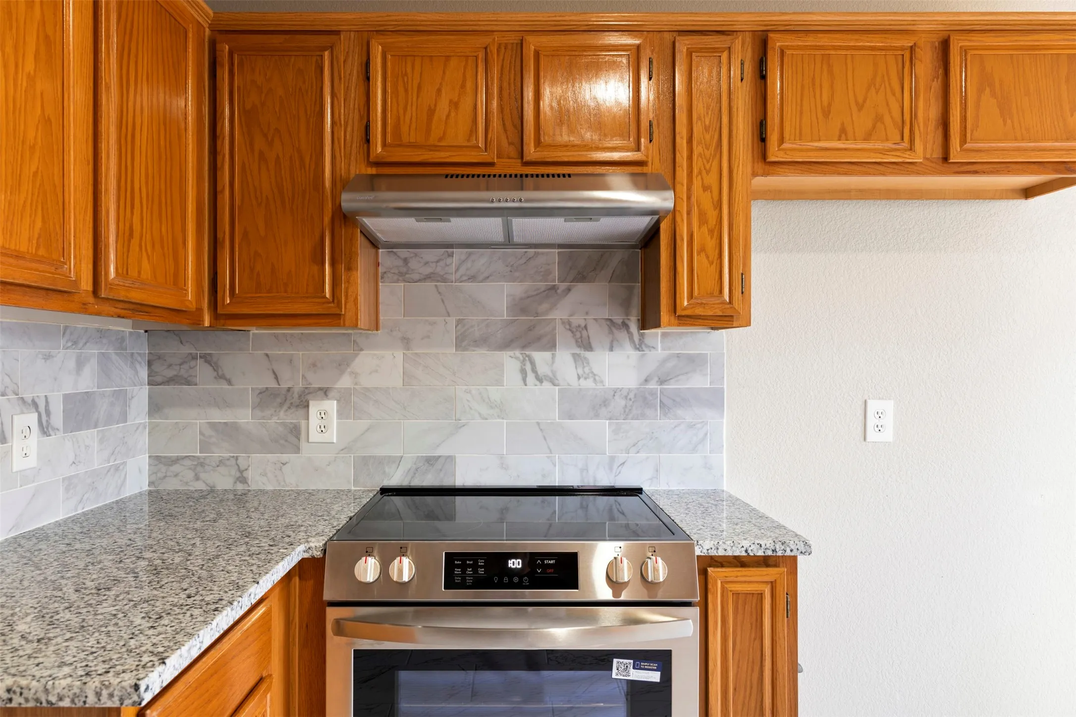 Kitchen featuring wood cabinetry, granite countertops, a subway tile backsplash, stainless steel range, and a coordinating range hood