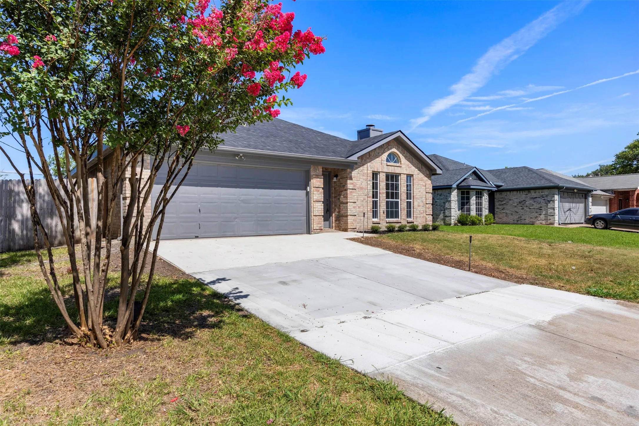 Contemporary brick facade with an attached two-car garage, concrete driveway, and a manicured lawn