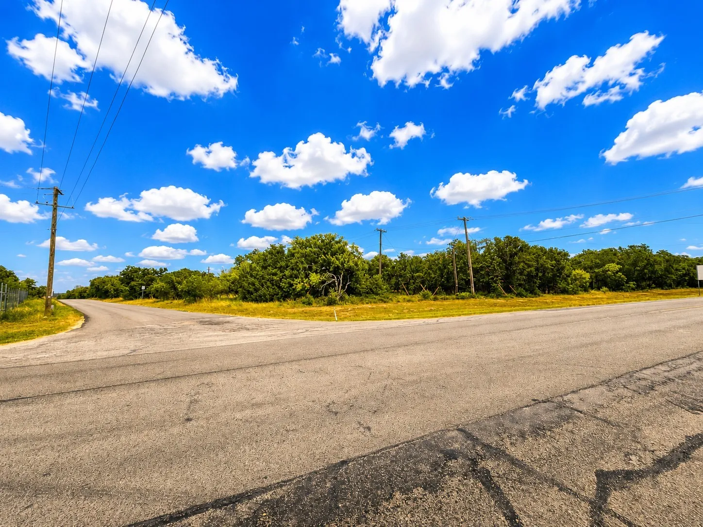 Paved road frontage with overhead utility access and mature tree line