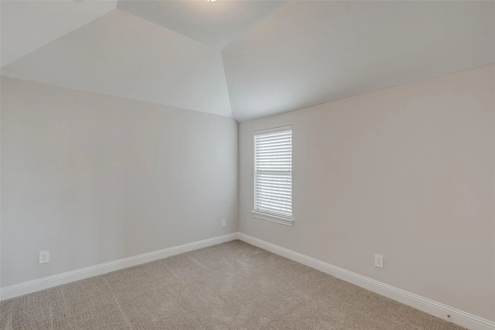 Bright room featuring neutral-toned carpeting, light gray wall paint, and white baseboards
