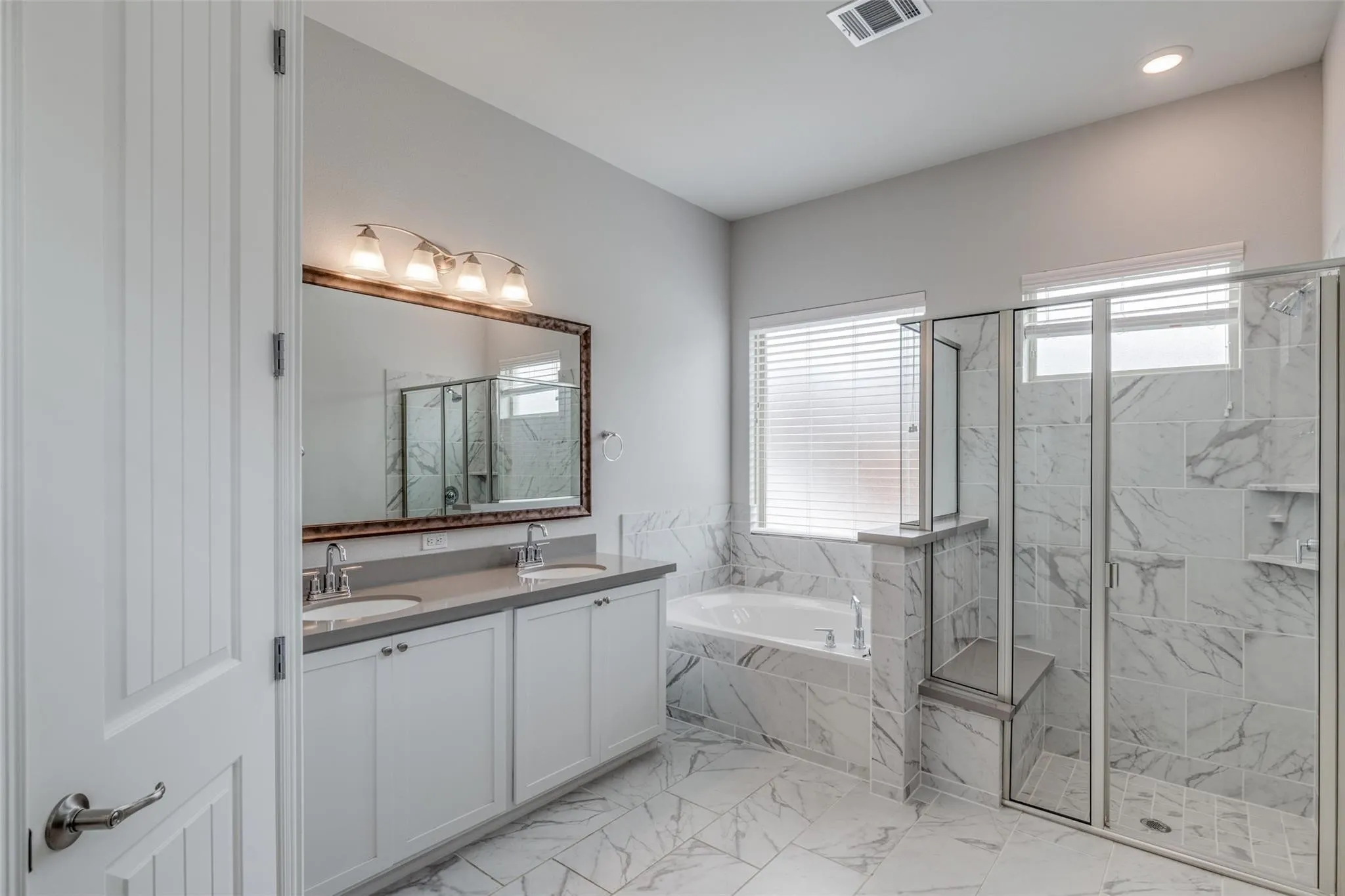 Spacious bathroom featuring a dual vanity with undermount sinks, a built-in soaking tub, and a separate glass-enclosed shower