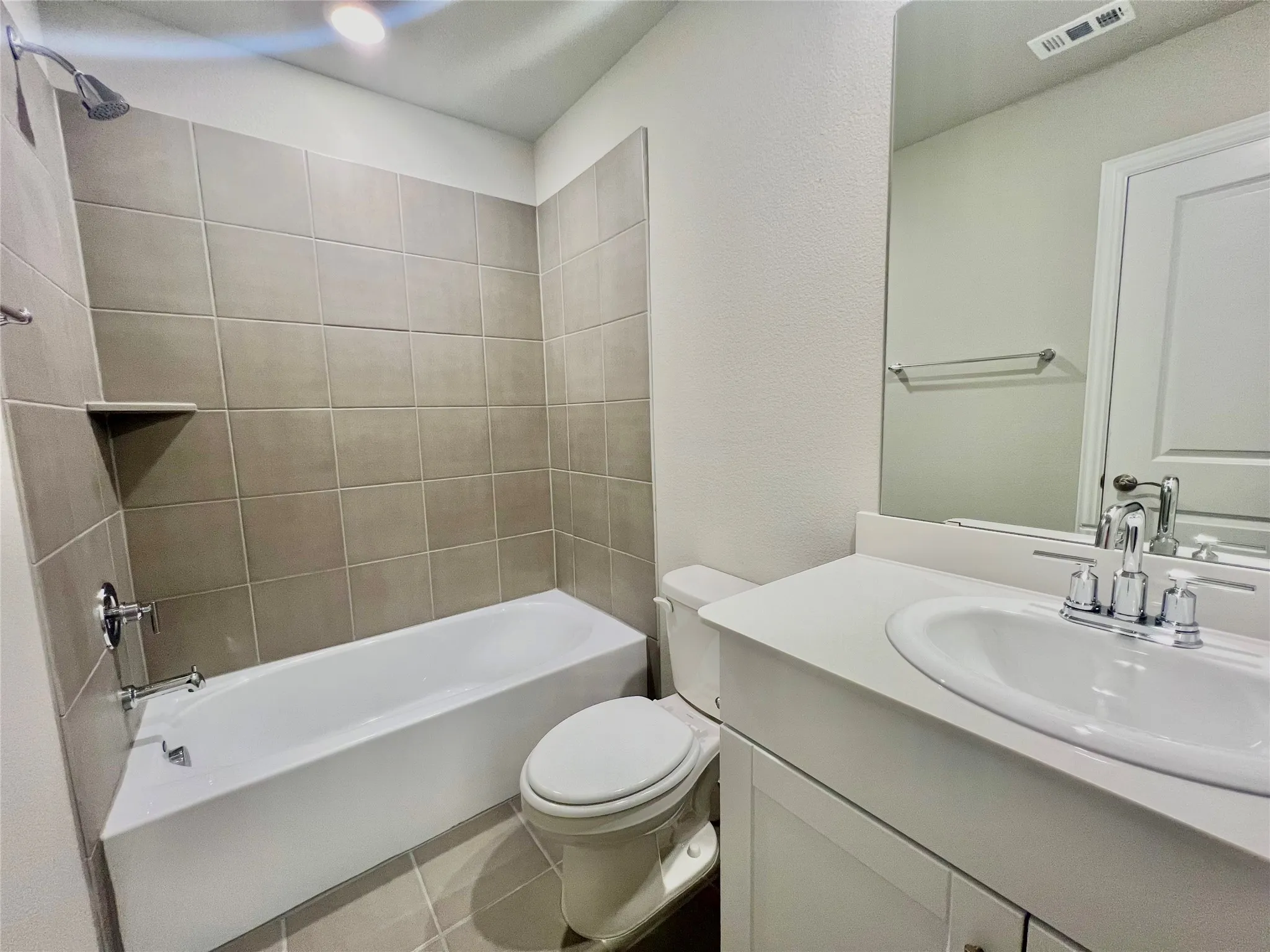 Bathroom featuring a white vanity with an integrated sink, chrome faucet, and expansive mirror