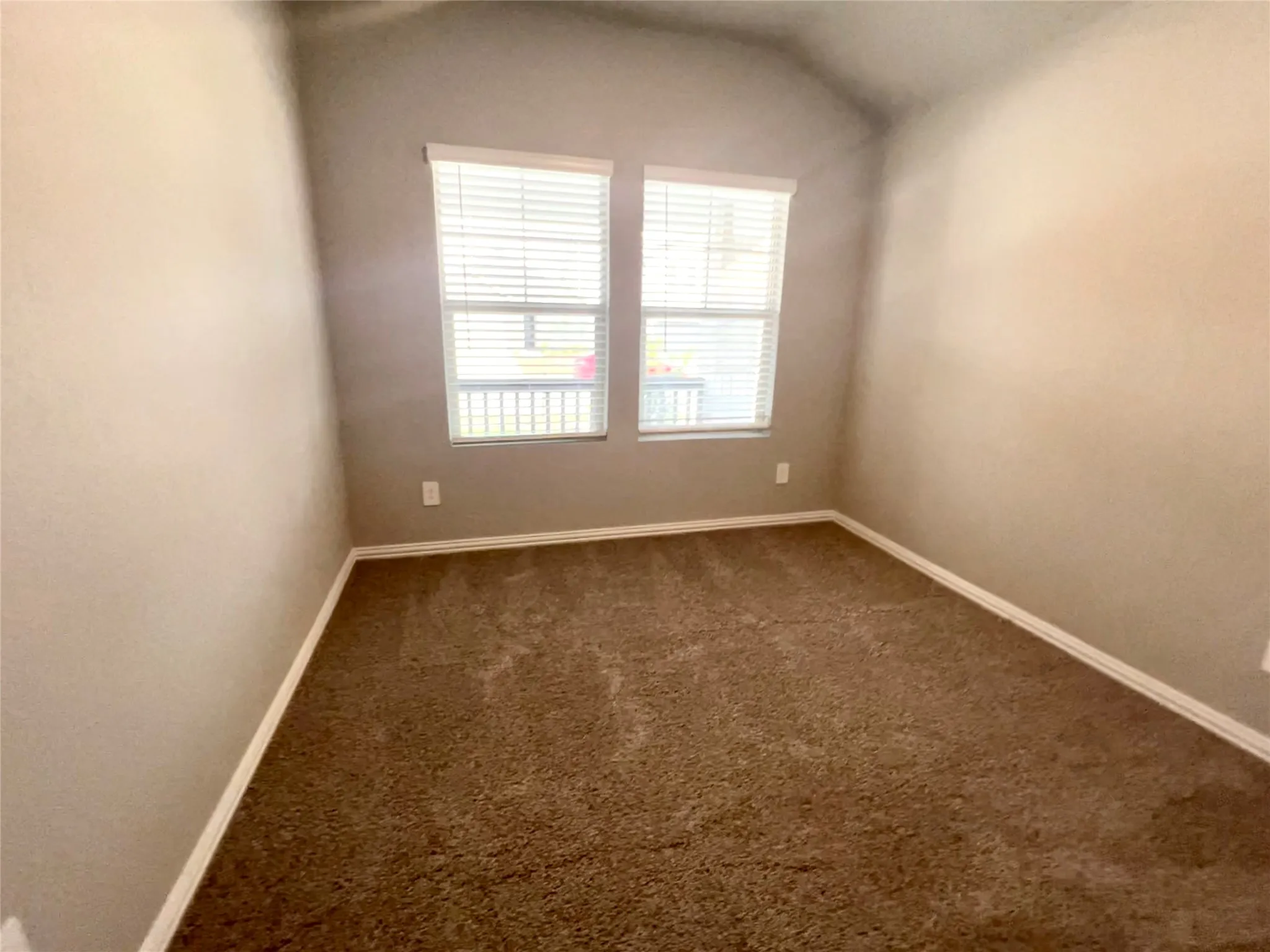 Room featuring brown carpet flooring, neutral-toned walls, and white baseboards
