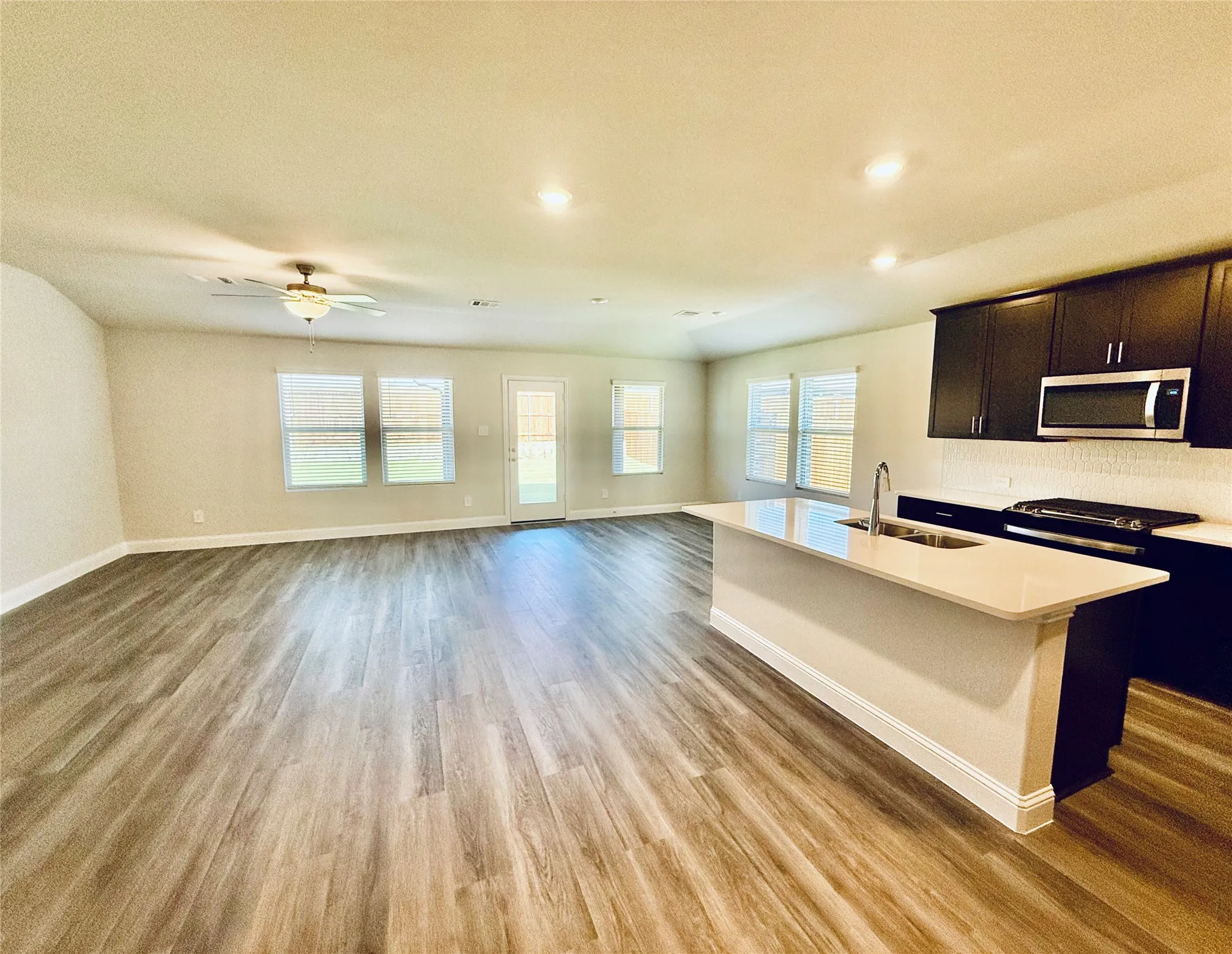 Spacious open-concept living area featuring wood-finish flooring, recessed lighting, and a ceiling fan