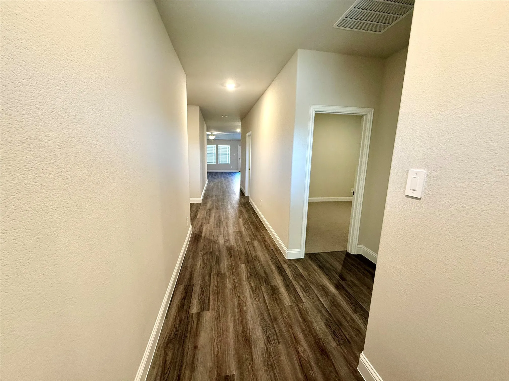 Long hallway featuring wood-finish flooring, recessed lighting, and neutral wall tones
