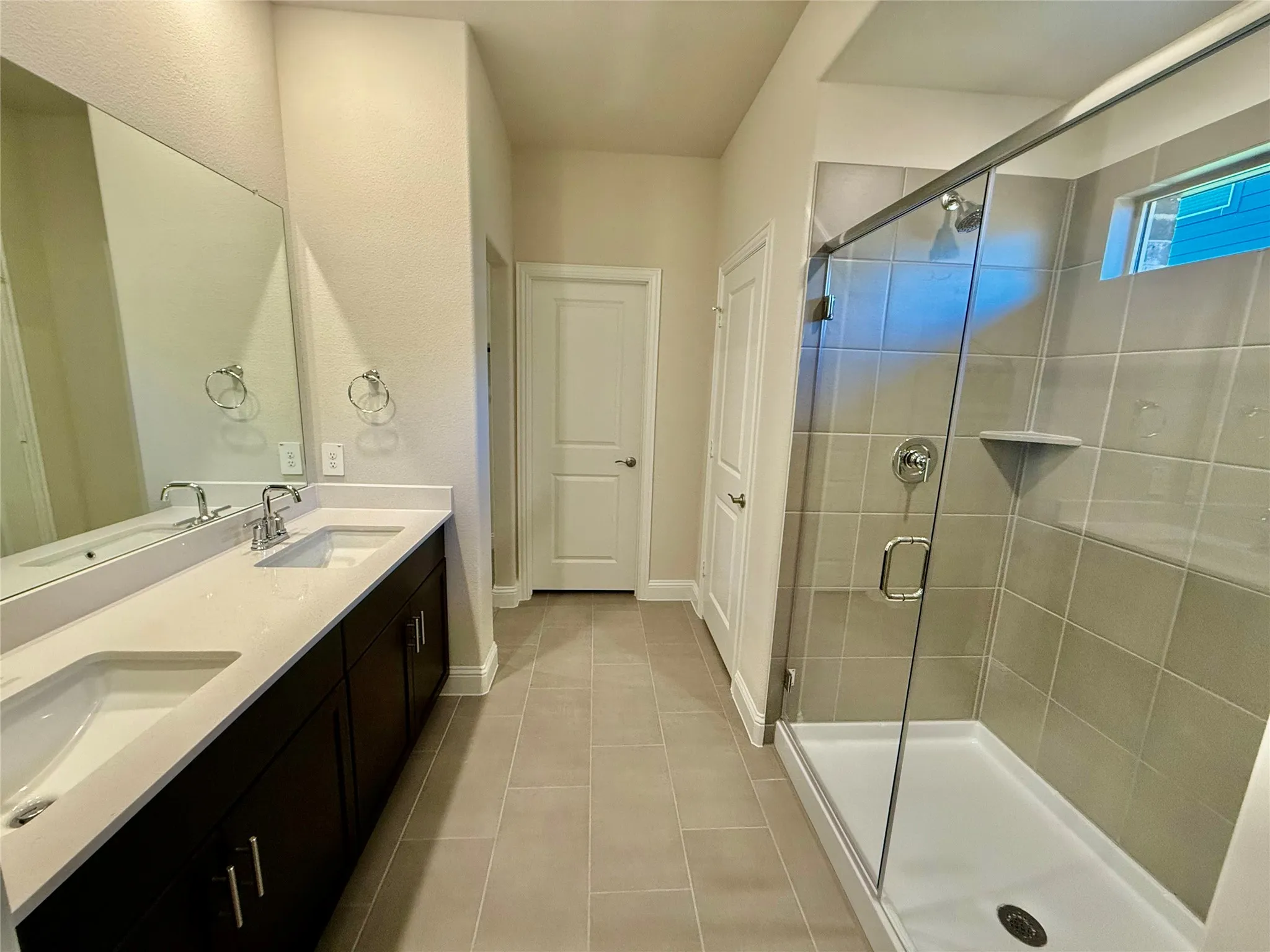 Bathroom featuring a dual-sink vanity with white countertops, dark wood cabinetry, and chrome fixtures
