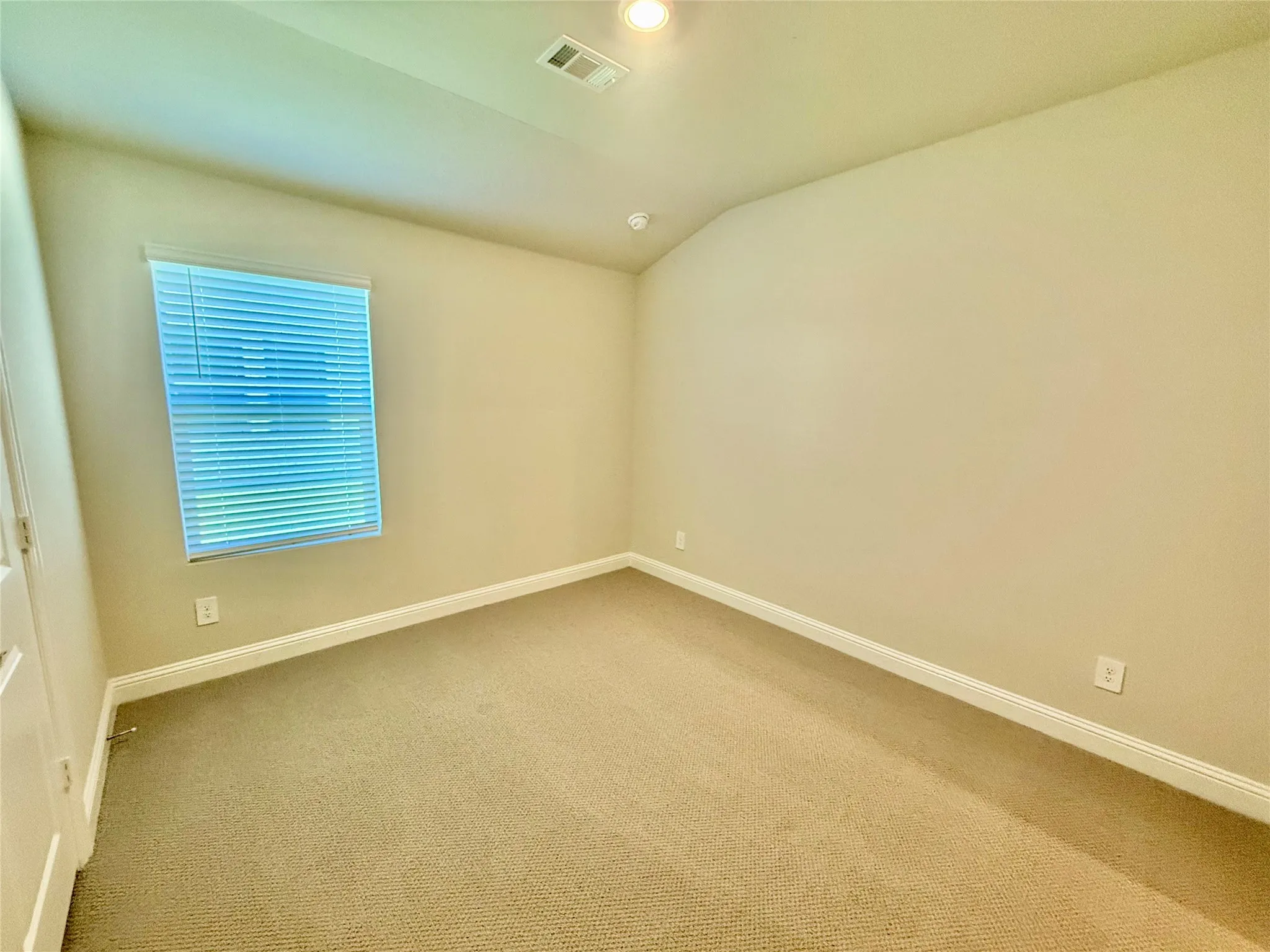 Neutral-toned room featuring a single window with blinds, recessed lighting, wall-to-wall carpeting, and white baseboards
