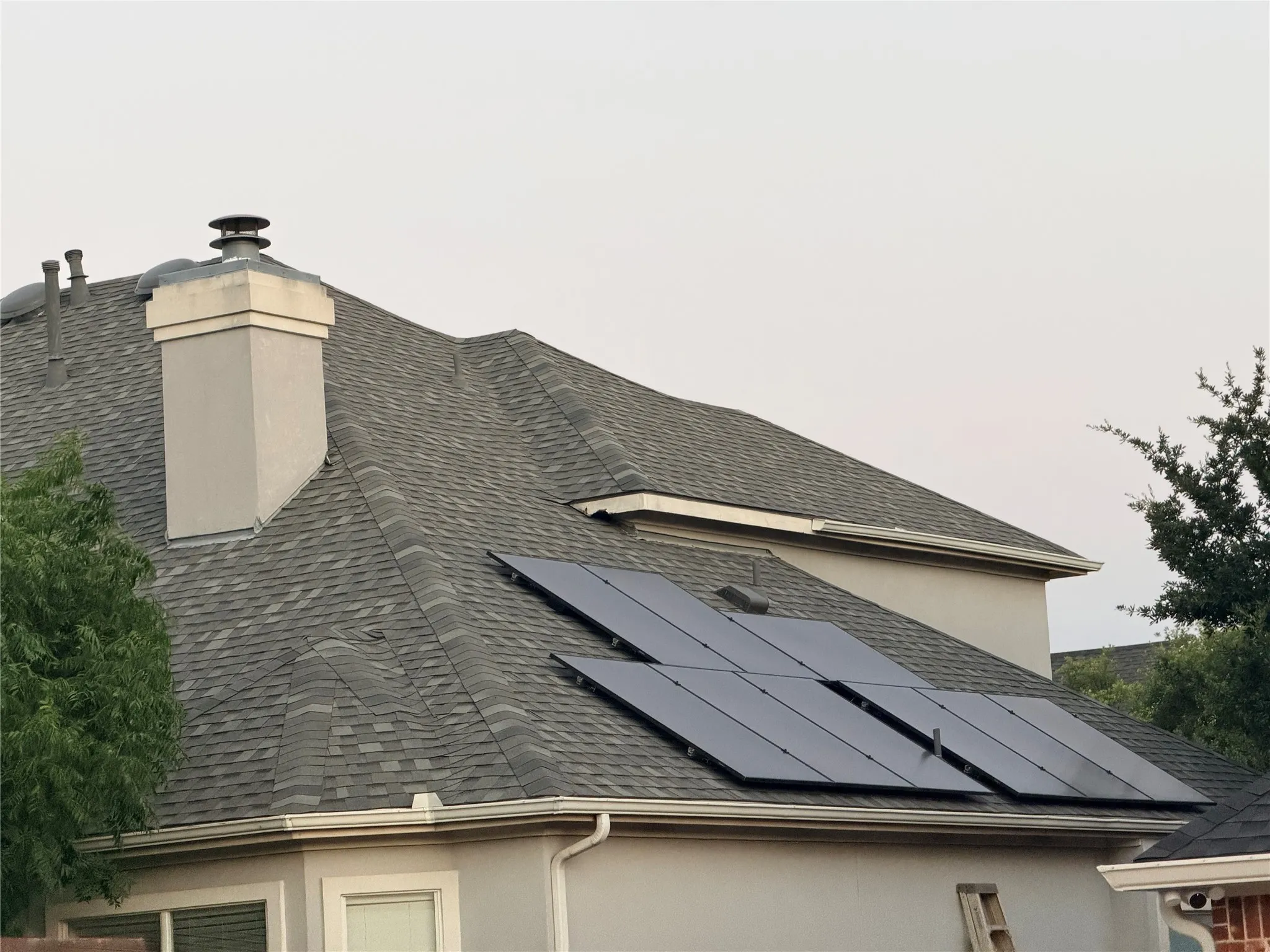 Gabled roofline with dark shingle roofing and fully paid solar panel