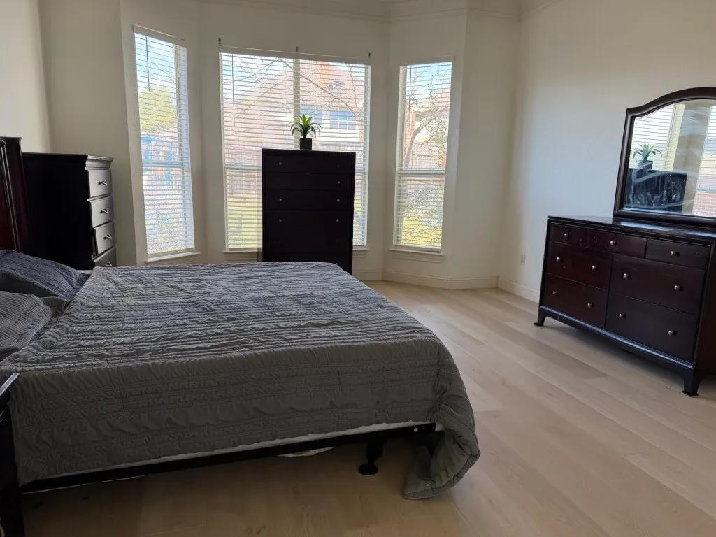 Bay window with multiple windows, light wood-finish flooring, white walls, and crown molding