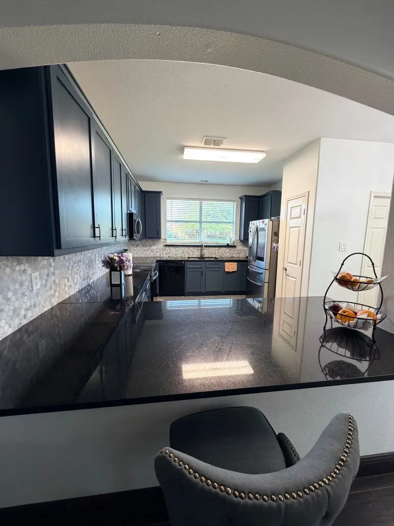 Kitchen featuring dark cabinetry, dark countertops, built-in appliances, and a mosaic tile backsplash