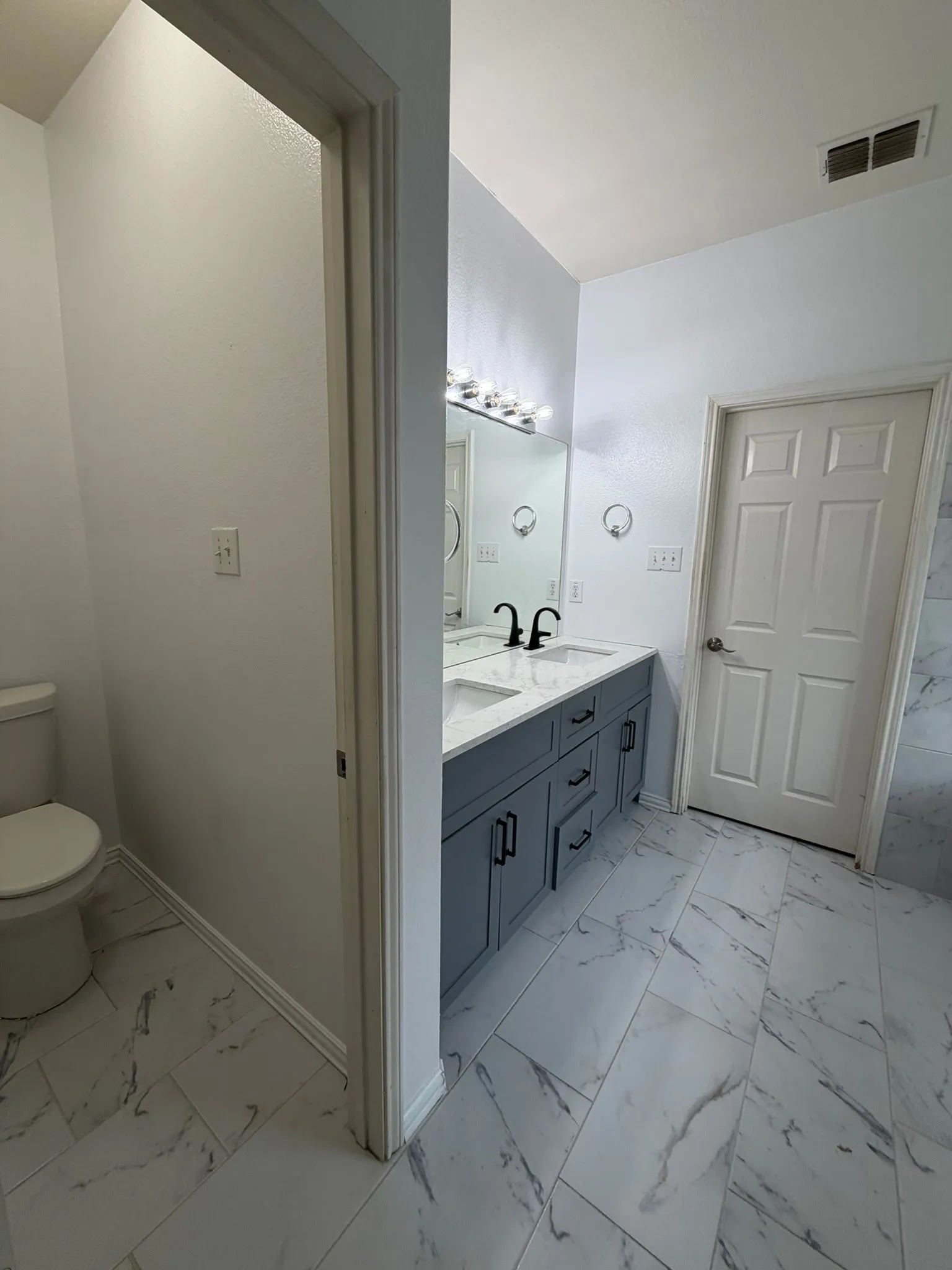 Modern bathroom featuring a dual vanity with a light gray cabinet, white countertop, and black fixtures