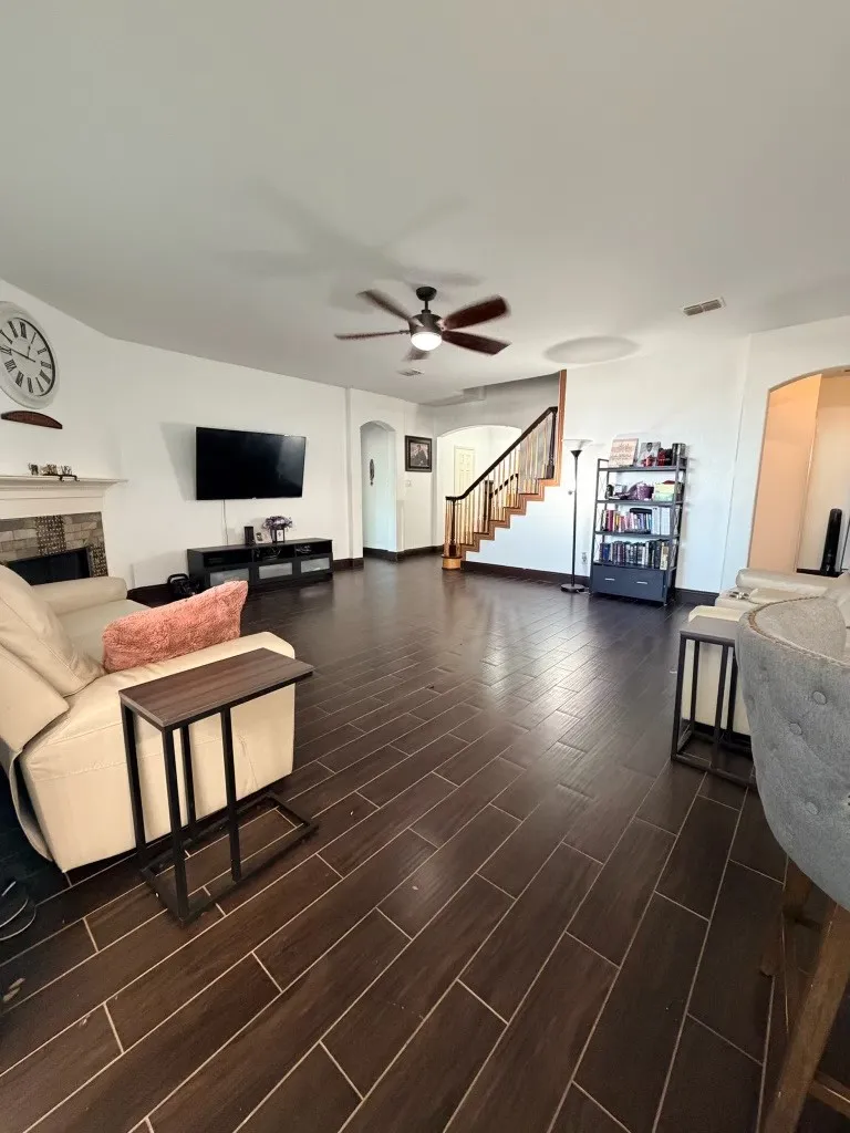 Spacious living area featuring plank-style tile flooring and a ceiling fan