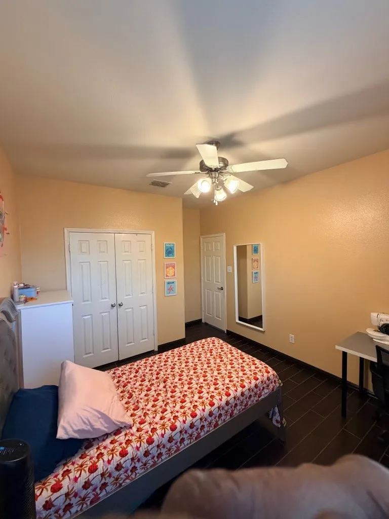 Room featuring wood-finish flooring, a double-door closet, and a ceiling fan with integrated lighting