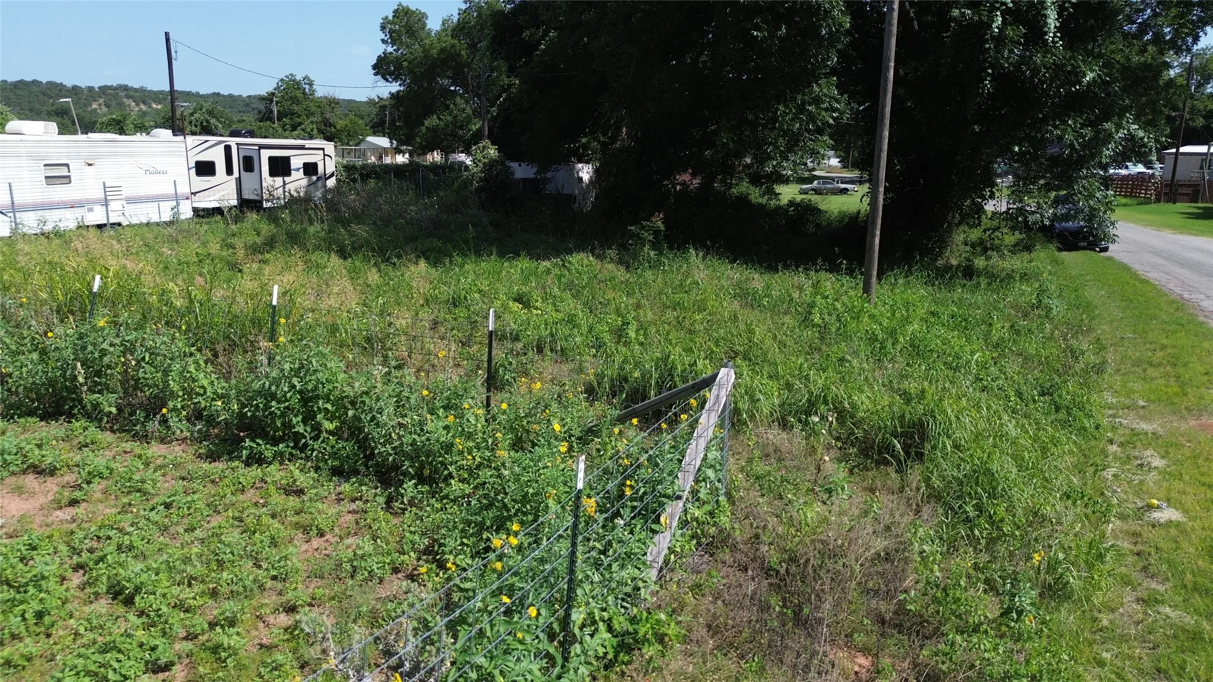 Expansive undeveloped lot featuring natural vegetation and partial fencing