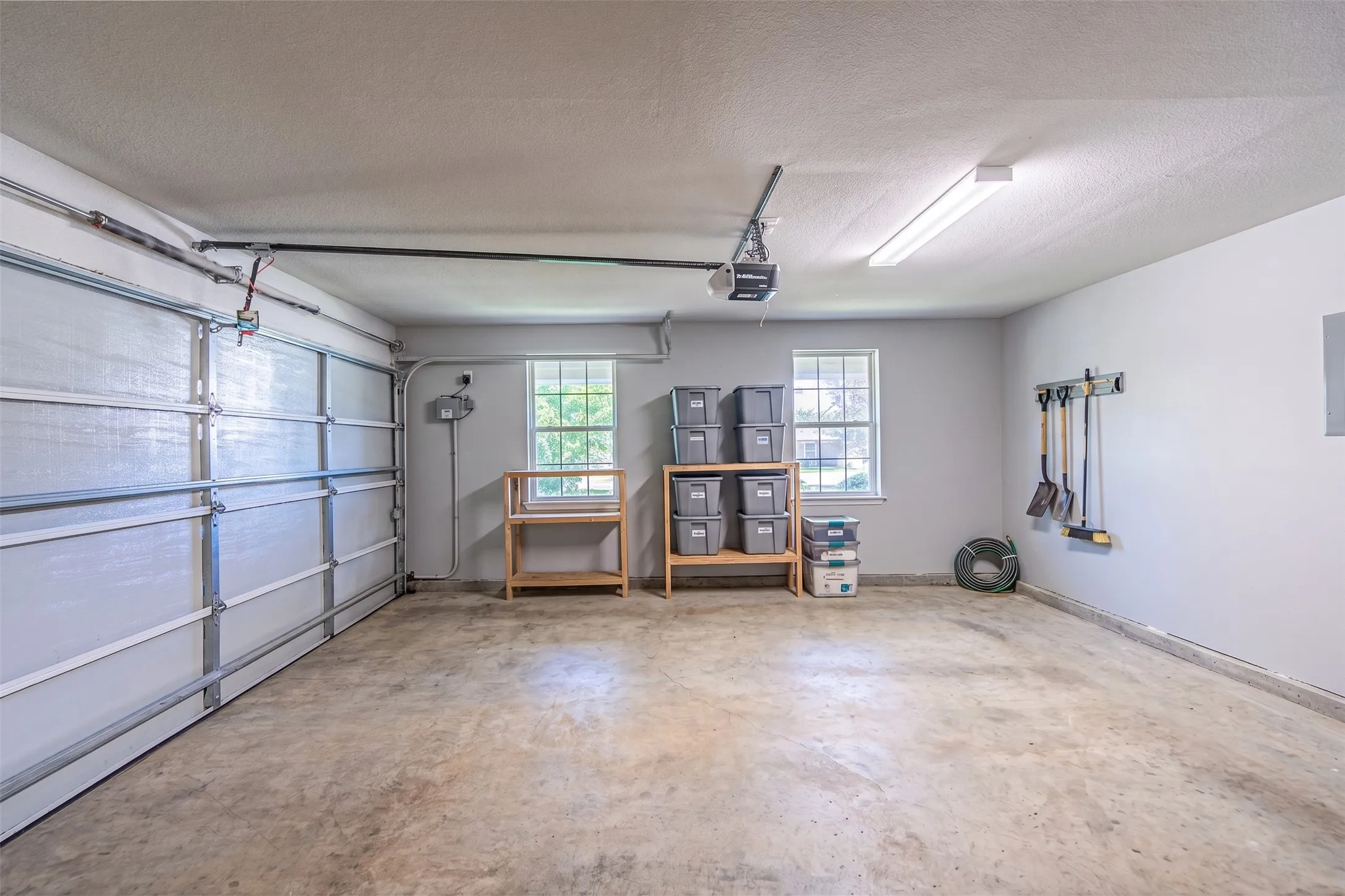 Attached garage featuring a concrete floor, two windows, and an overhead garage door with opener