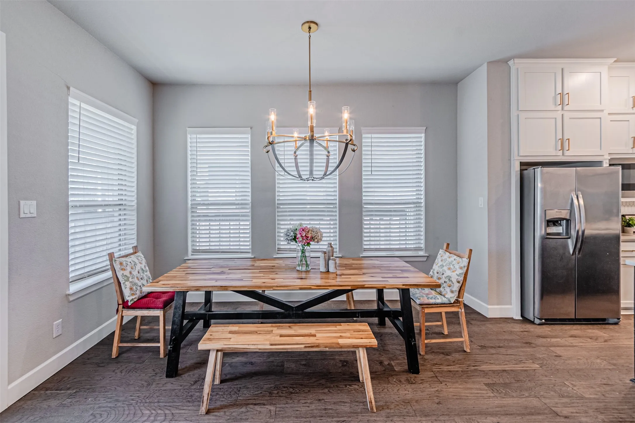 Hardwood-style flooring, white built-in cabinetry, and a stainless steel refrigerator