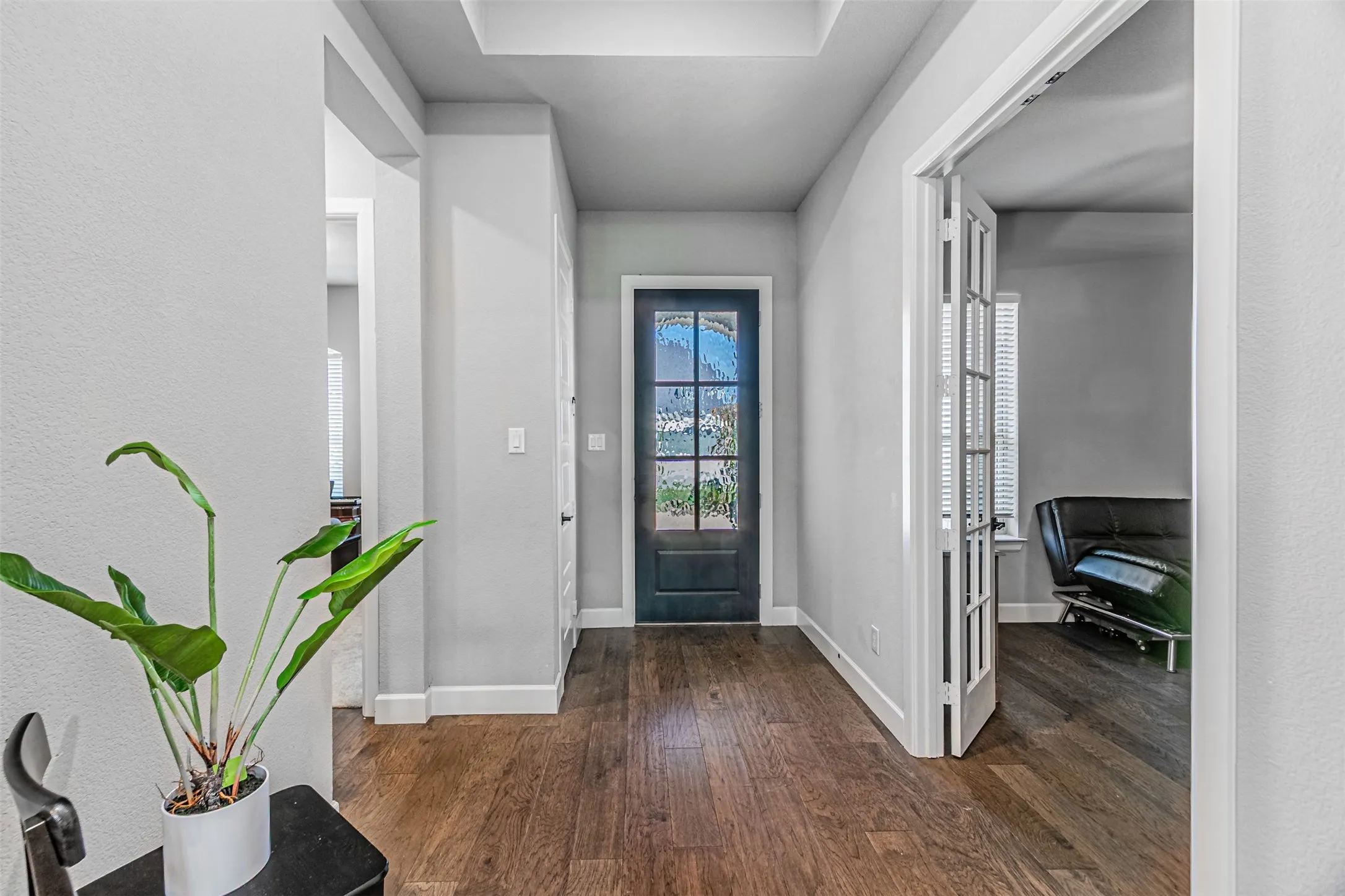 Wood-finish flooring, recessed lighting, and a dark-paneled entry door