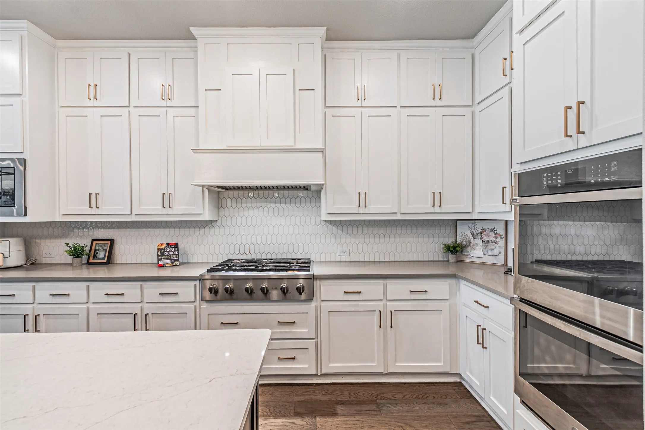 White shaker cabinetry, stainless steel appliances, built-in double oven, gas range, and white subway tile backsplash