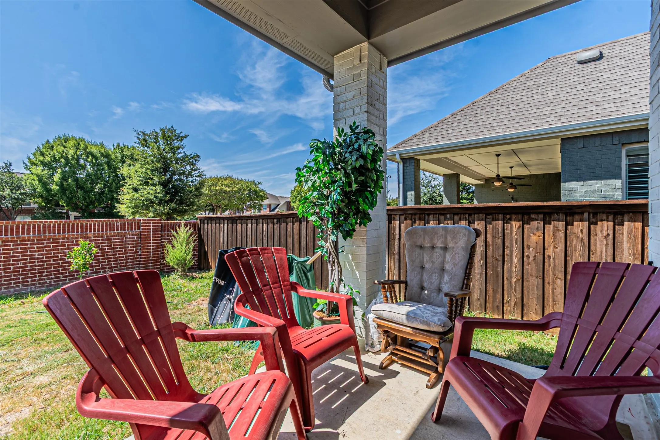 Covered patio with brick support column, concrete flooring, and privacy fencing