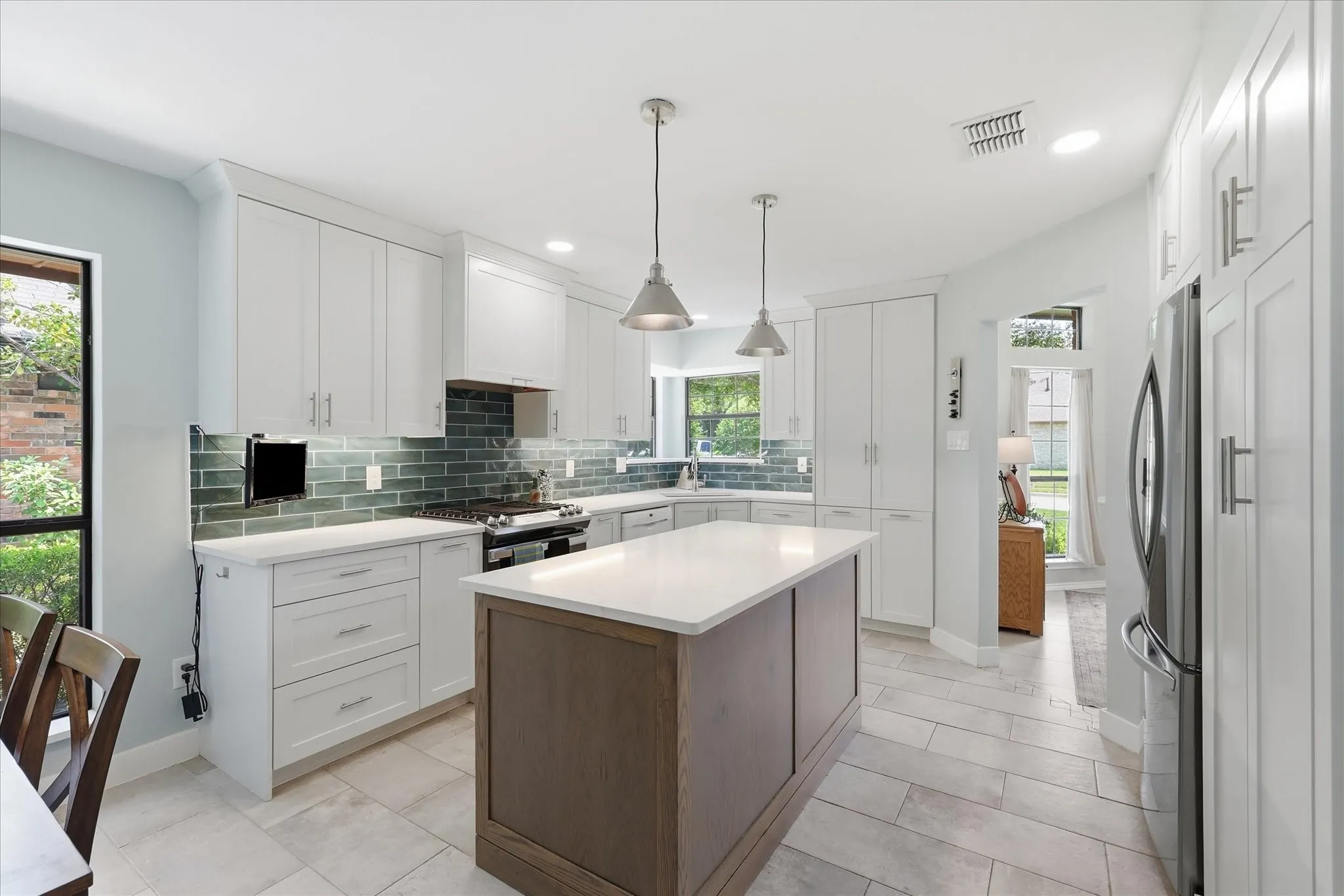 Completely updated kitchen featuring white quartz countertops with slight veining which allows the dark greenish blue subway tile to stand out.