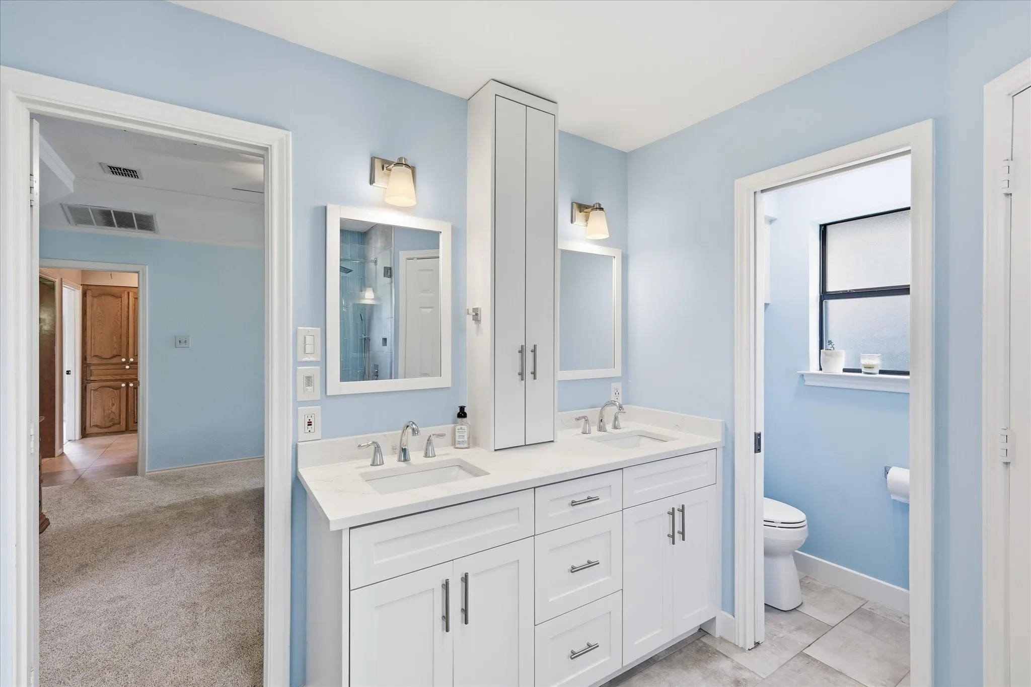 Double sinks and tower storage.  There is a pocket door to give some privacy to the toilet area.  There is also additional storage over the toilet.