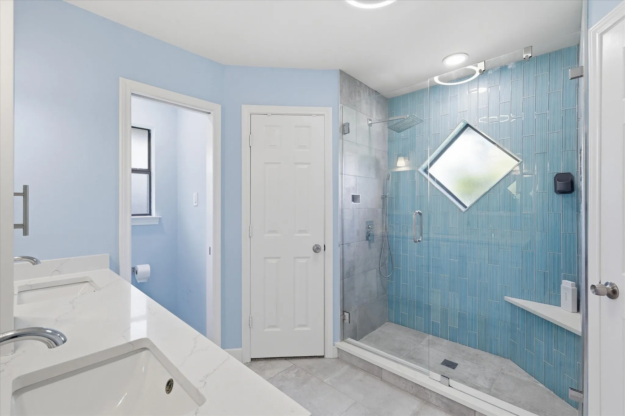 Updated primary bathroom.  Roomy walk in shower with pretty blue tiles to resemble a waterfall.  Bath also features his and hers walk in closets.