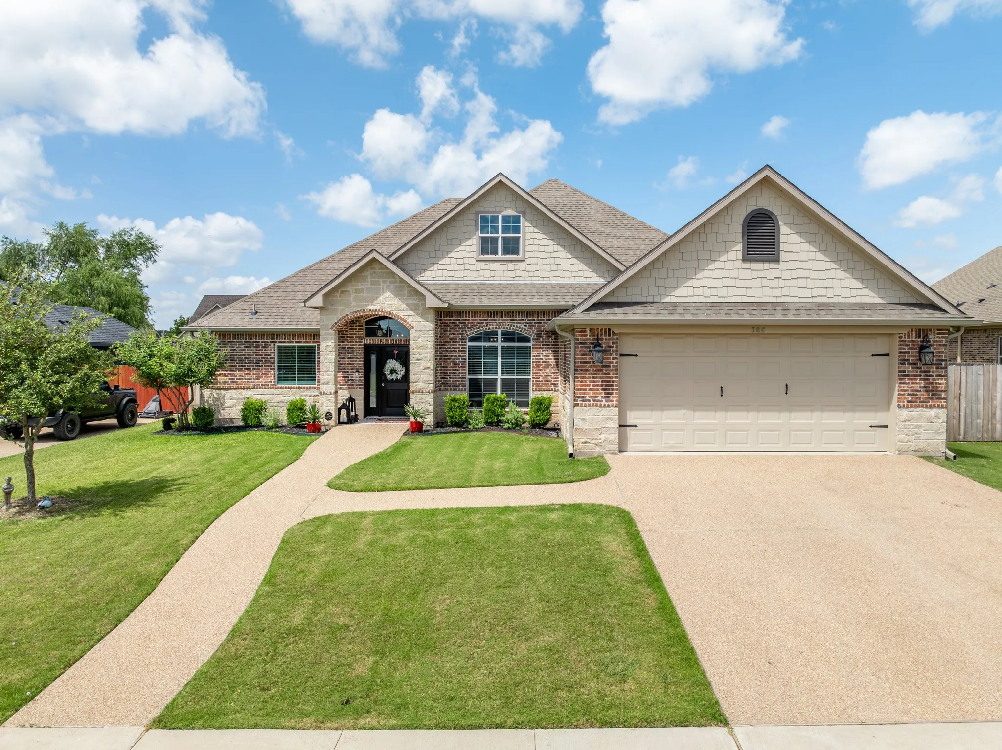 Brick and stone facade featuring a gable roofline and a two-car garage