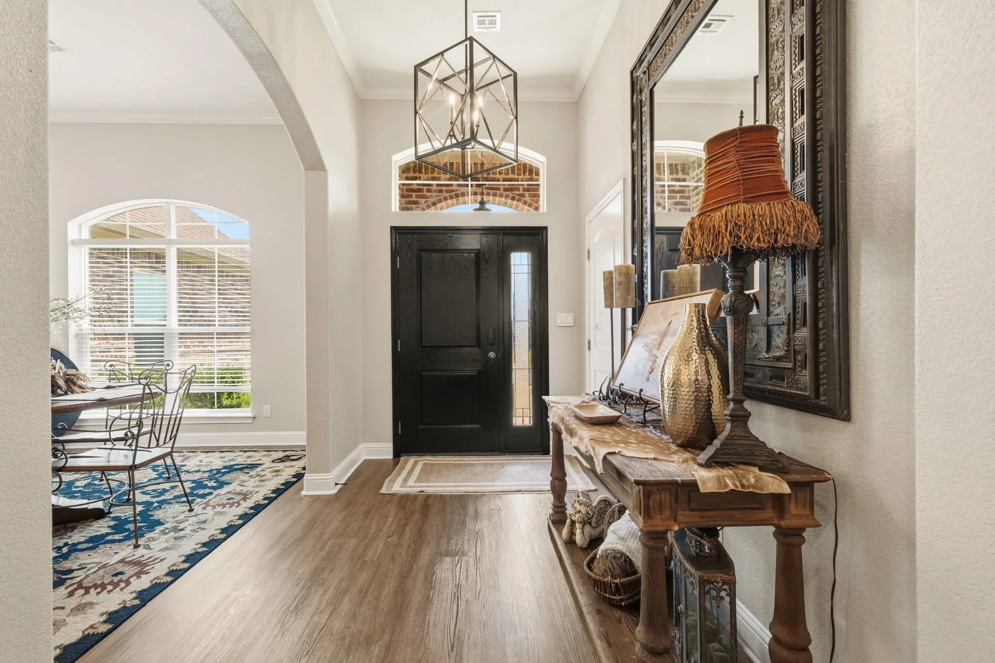 Welcoming entryway featuring a dark-paneled door with sidelight, transom window, and a geometric pendant light fixture