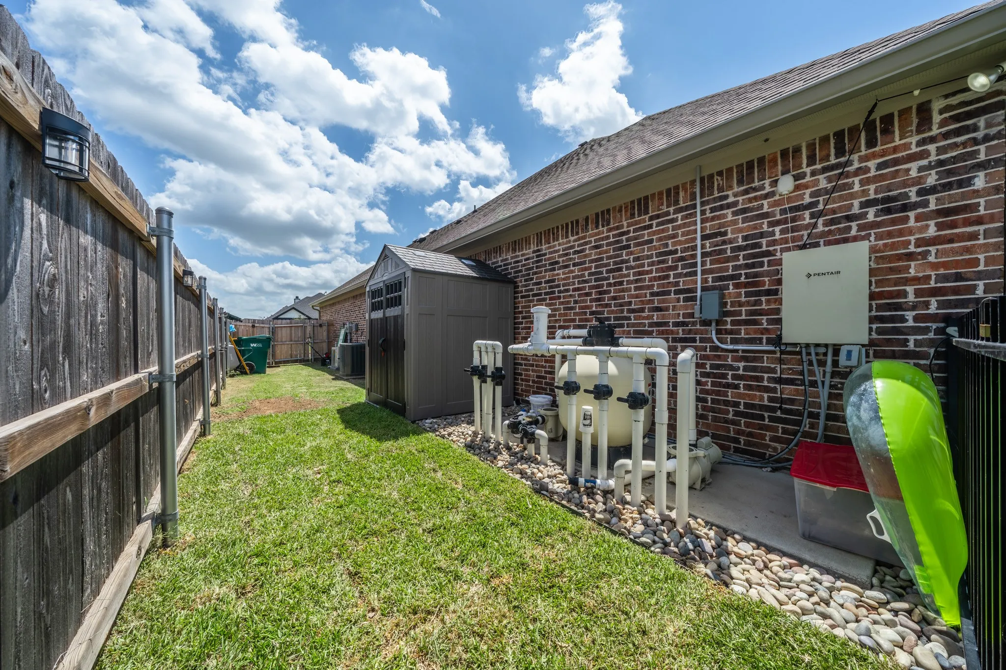 Expansive side yard featuring a wooden privacy fence and a dedicated area with pea gravel landscaping