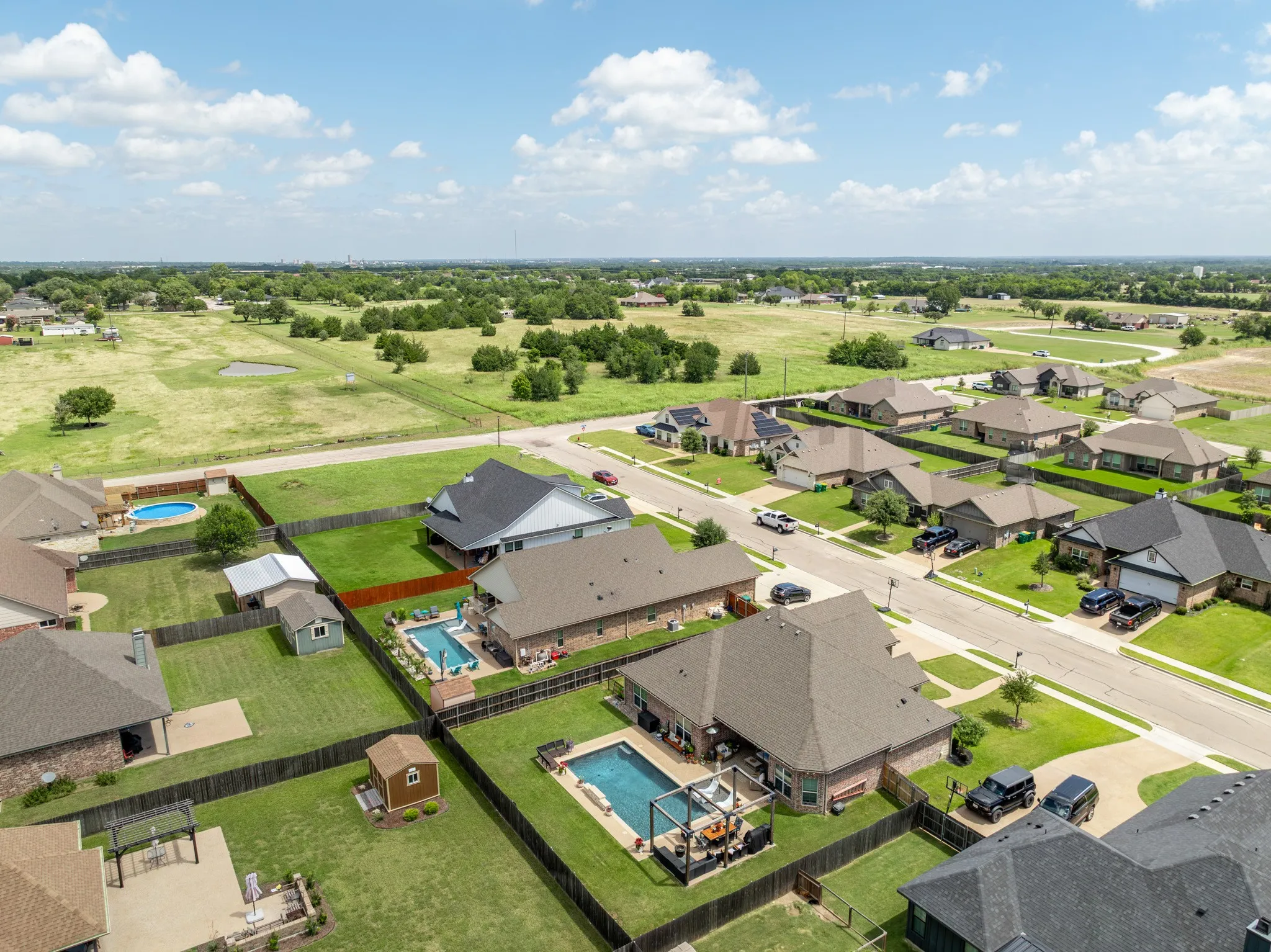 Aerial perspective showcasing a residential community with individual homes, fenced backyards, and mature landscaping