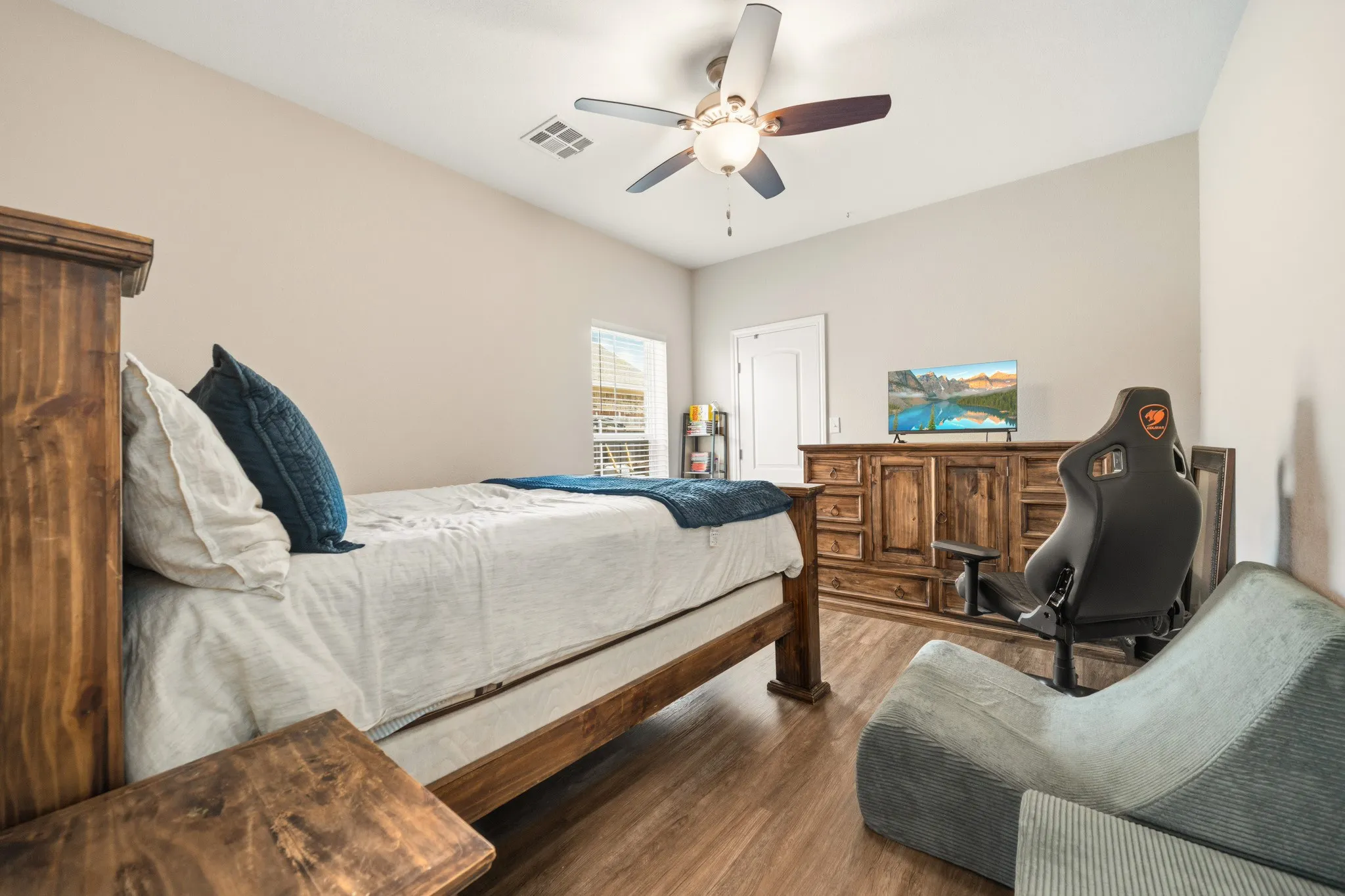 Bedroom featuring wood-finish flooring, a vaulted ceiling, a ceiling fan with integrated lighting, and a window with horizontal blinds