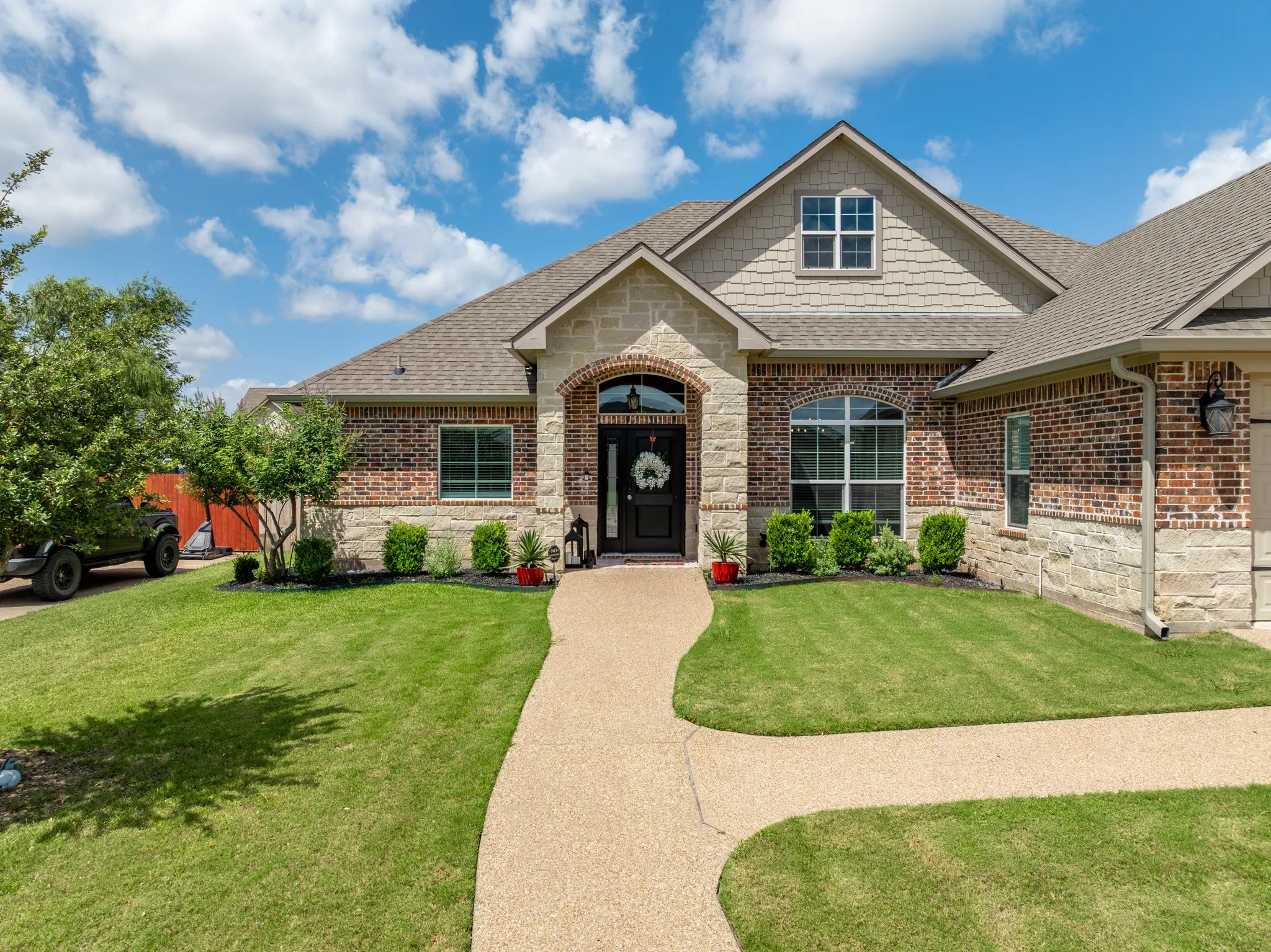 Traditional-style residence featuring a combination brick and stone facade, an arched entry, and a gabled roofline