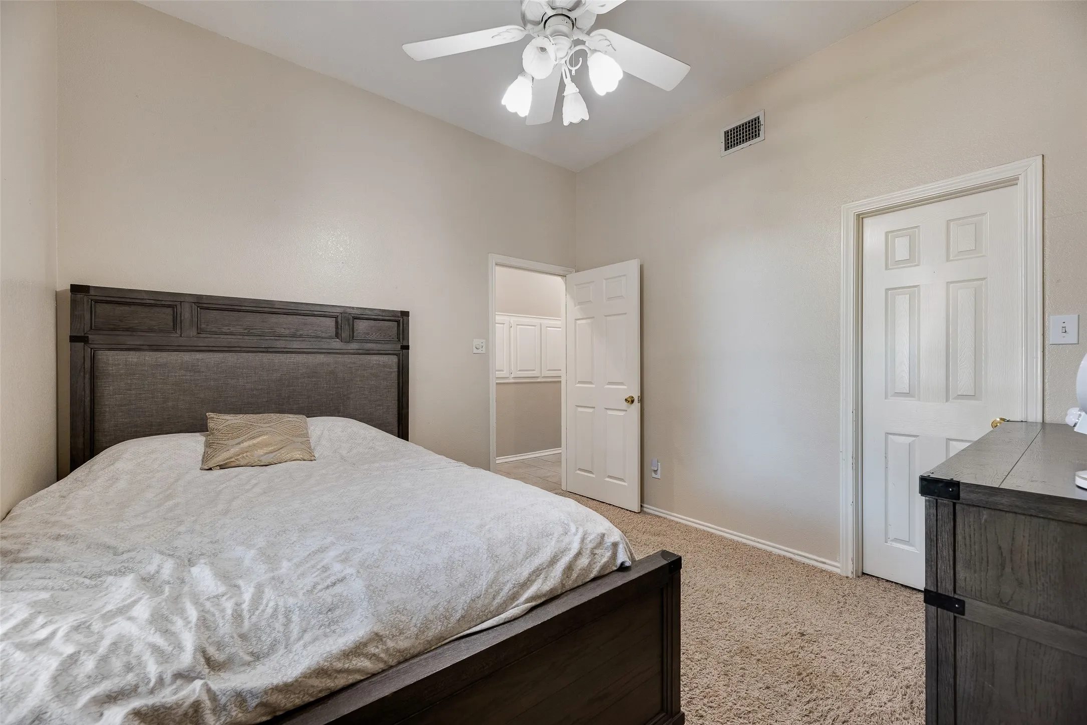 Carpeted bedroom featuring vaulted ceilings and a ceiling fan with light fixture