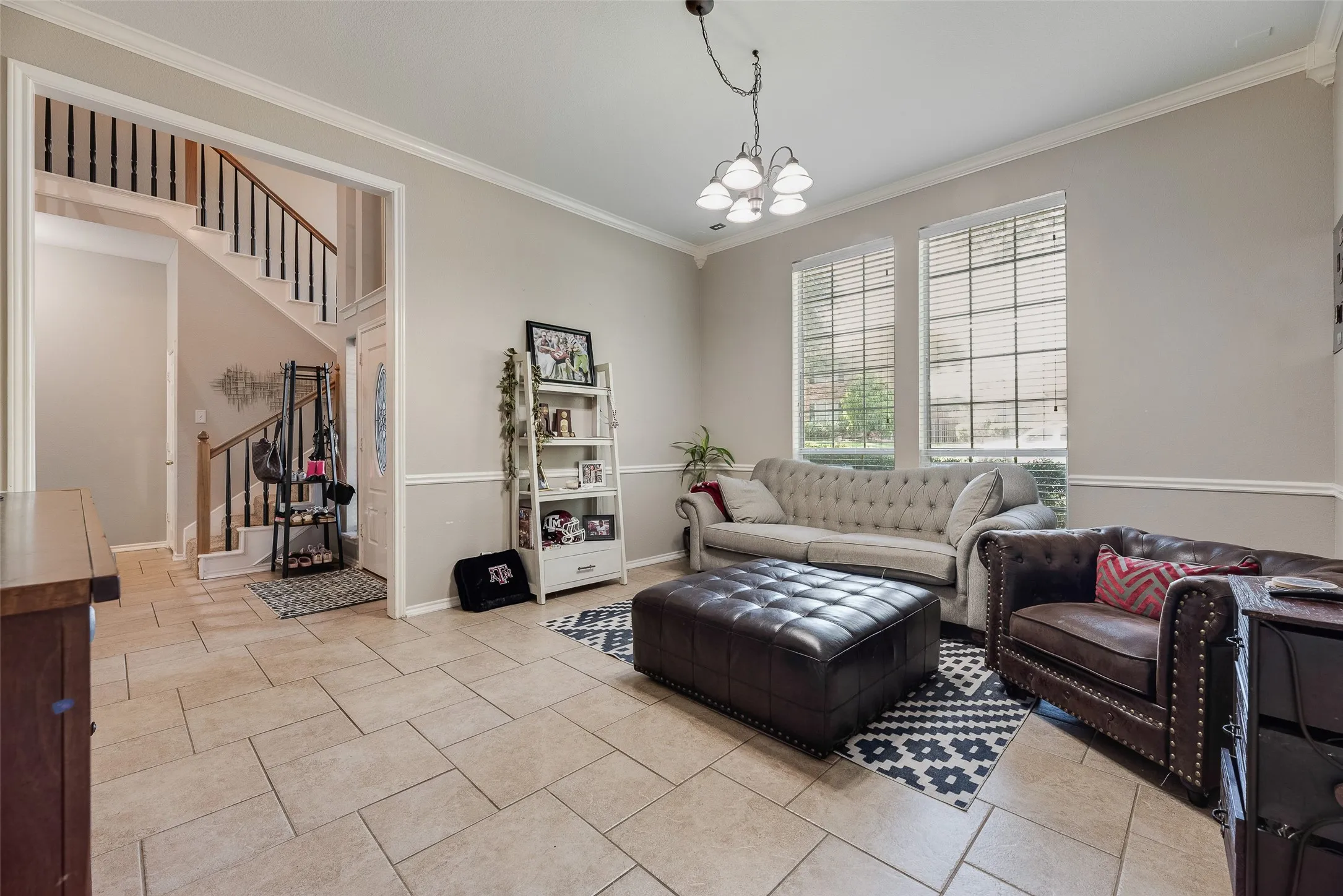 Spacious living area featuring neutral wall tones, crown molding, and wainscoting