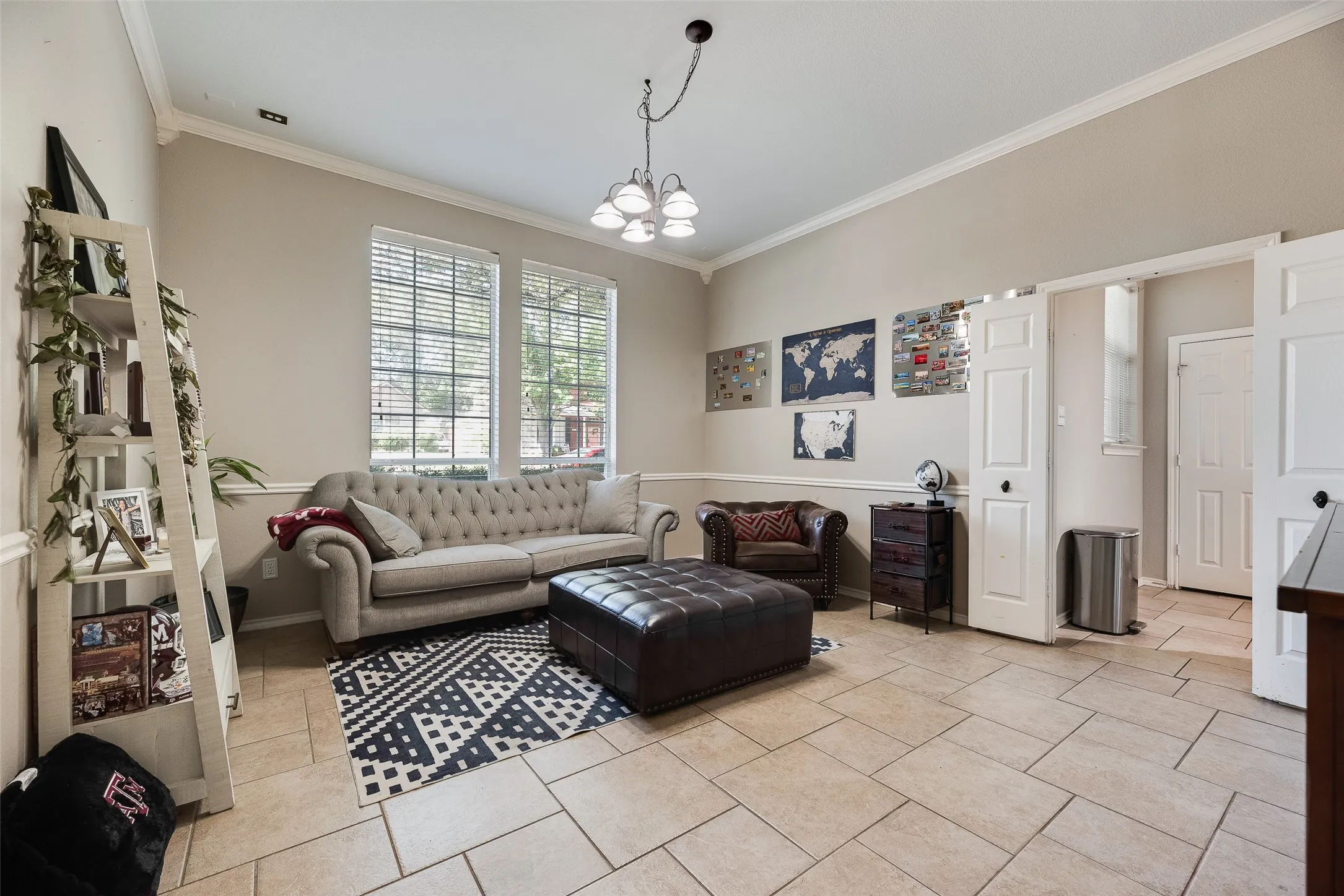 Spacious room featuring tile flooring, vaulted ceilings, crown molding, and multiple windows with blinds