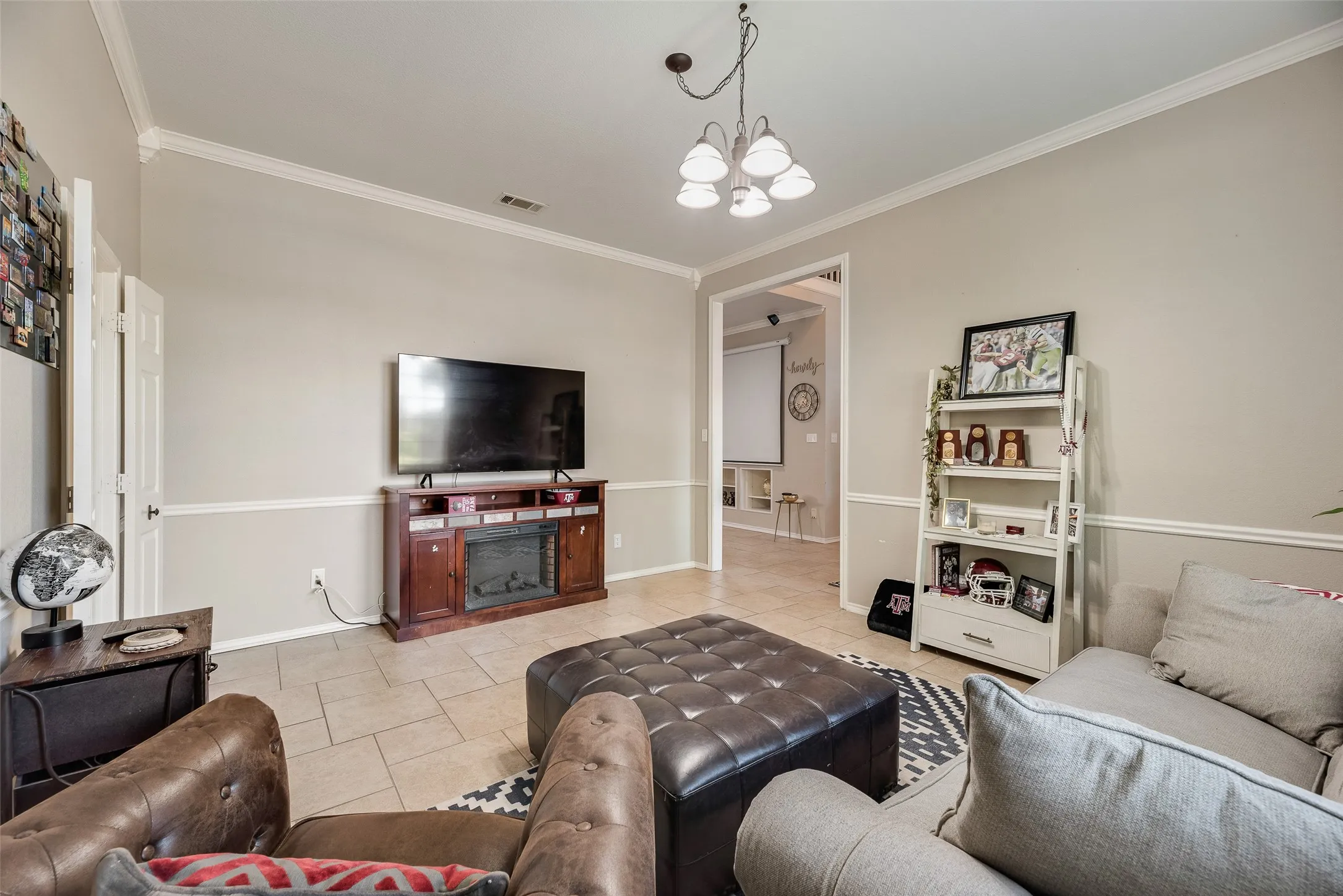 Living area featuring tile flooring, crown molding, and a chair rail accent