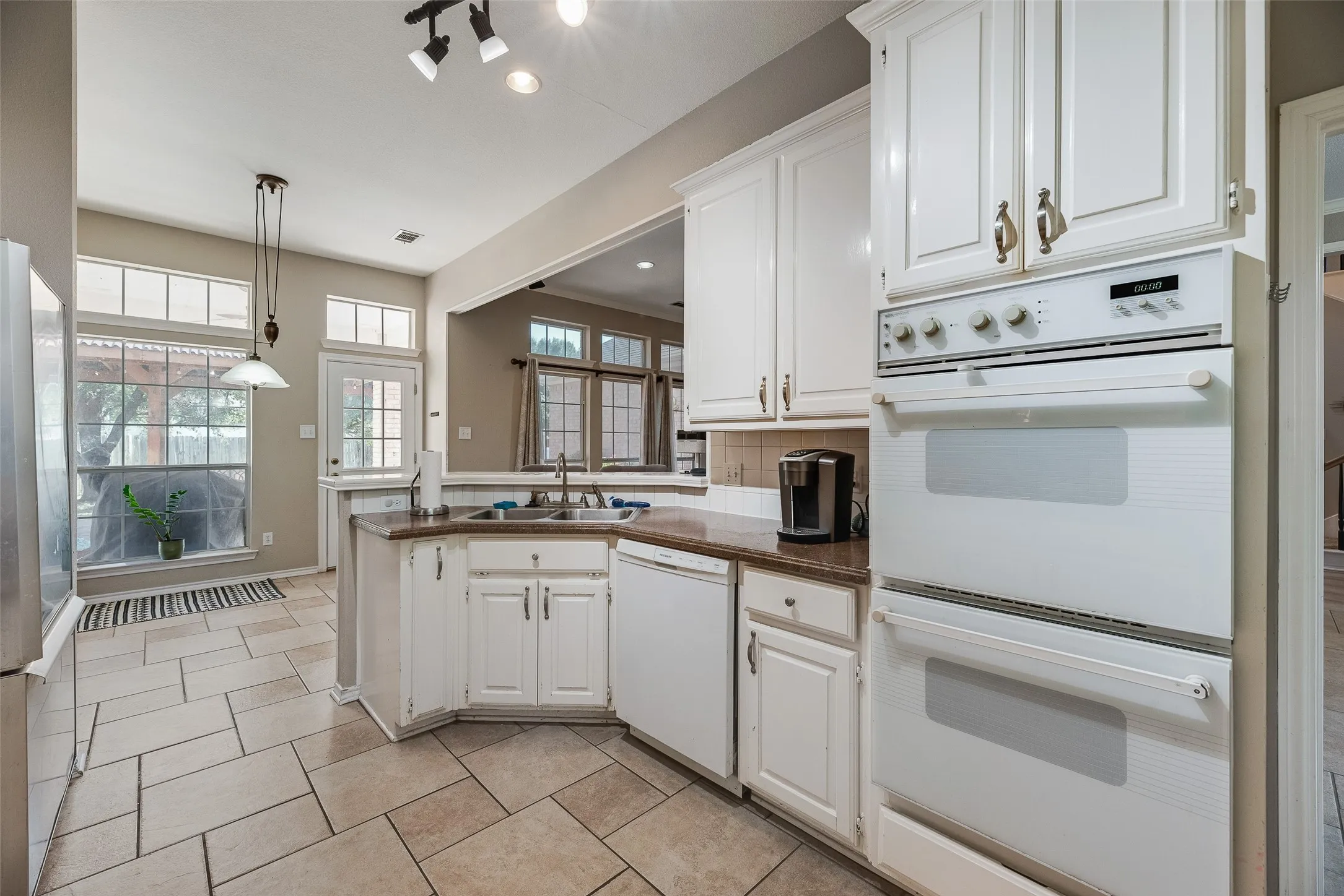 Kitchen featuring white cabinetry with gold-toned hardware, a double wall oven, and tile flooring