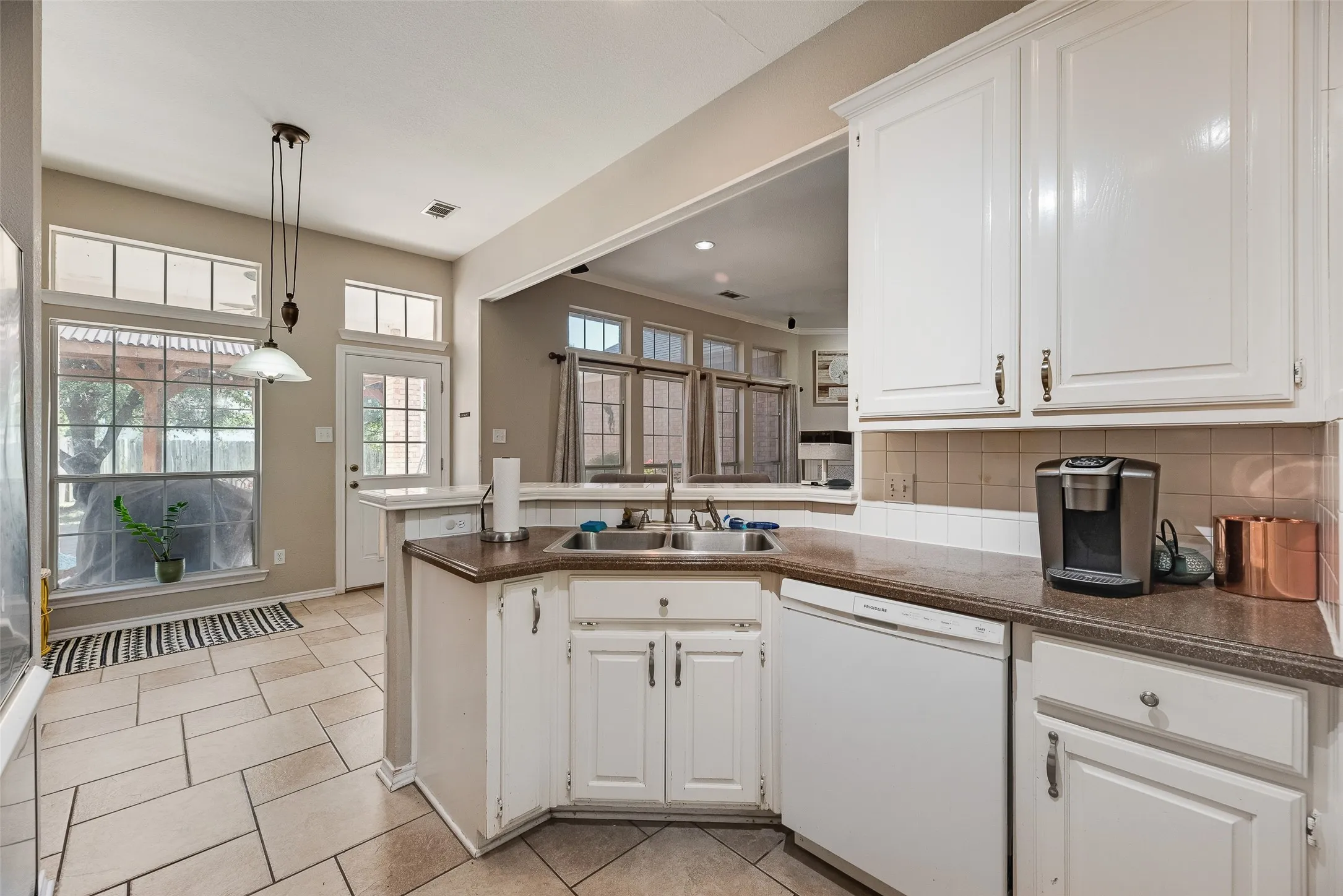 Kitchen featuring white cabinetry, solid surface countertops, tile flooring, and integrated sink