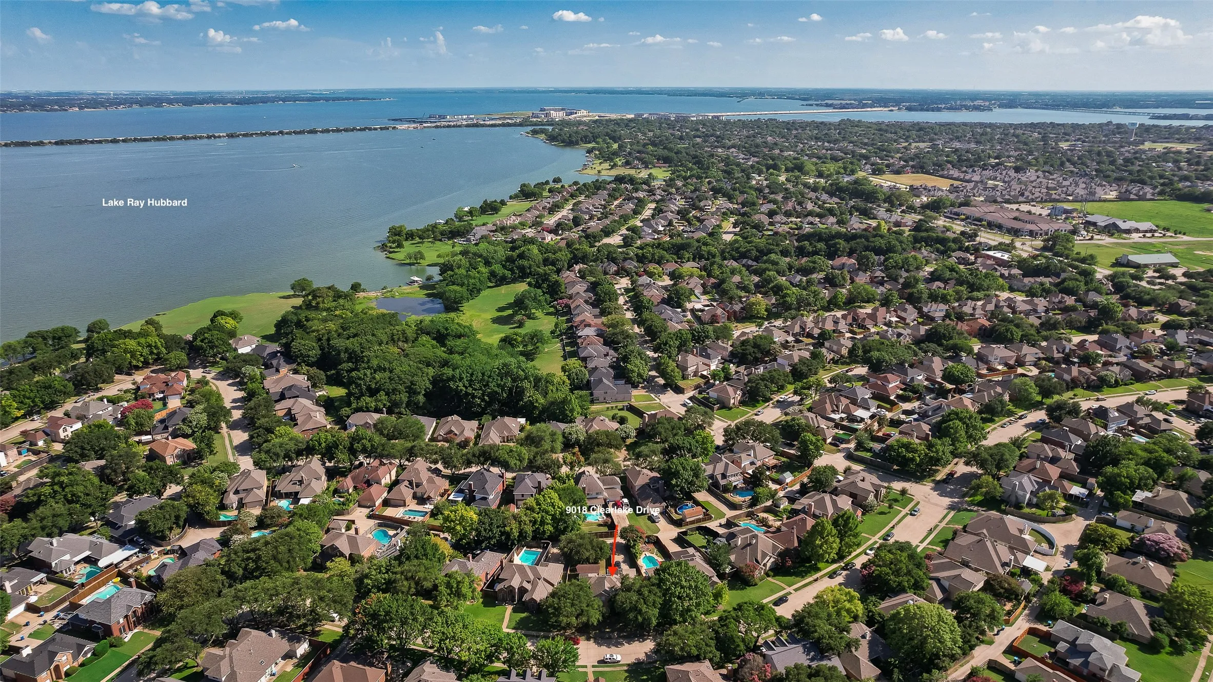 Expansive aerial perspective showcasing a residential development bordering a substantial body of water, identified as Lake Ray Hubbard